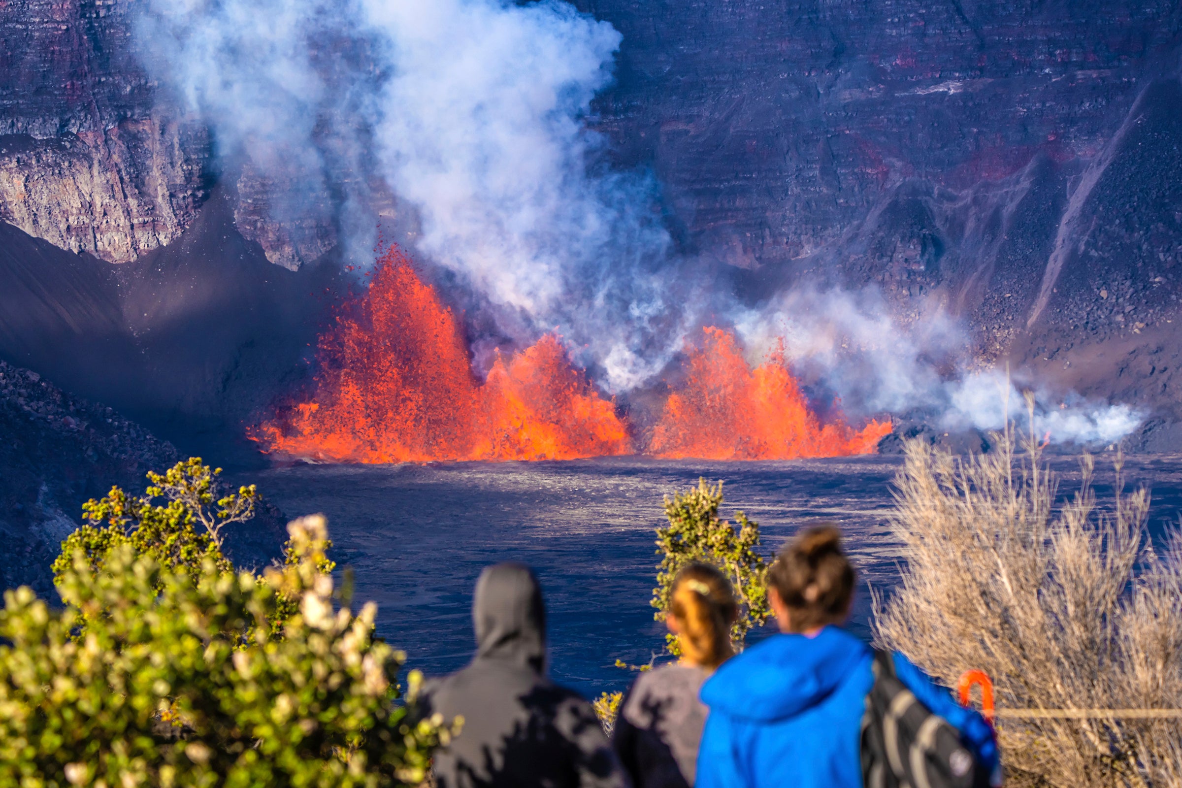 People watch as an eruption takes place on the summit of the Kilauea volcano in Hawaii on Monday. The volcanic eruption, which started on Monday, is now in its second pause. But, park officials are issuing a warning to visitors after an almost disastrous incident occurred near the volcano