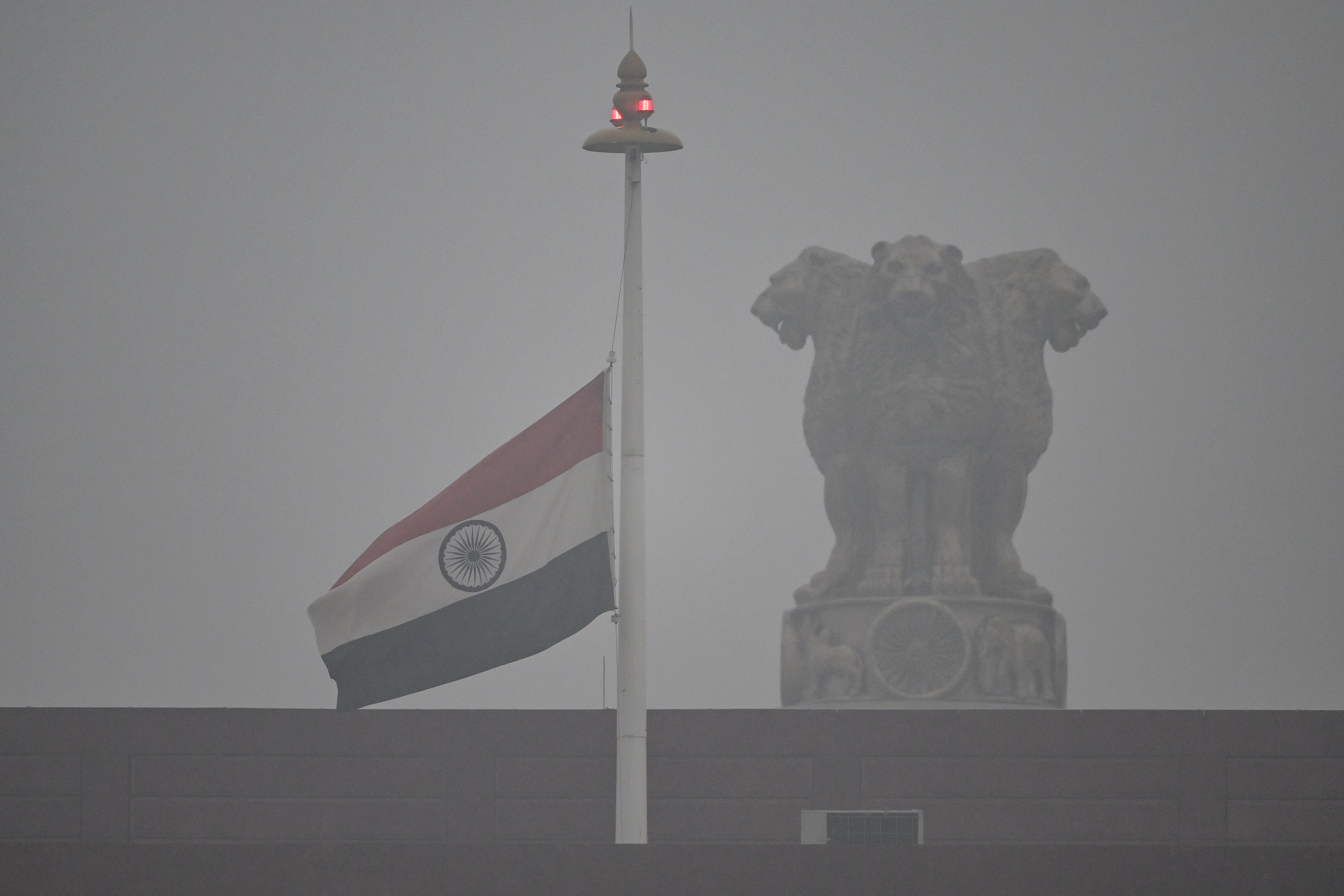 The Indian national flag flies half-mast at the Parliament to mourn the death of former Indian prime minister Manmohan Singh as it rains in New Delhi