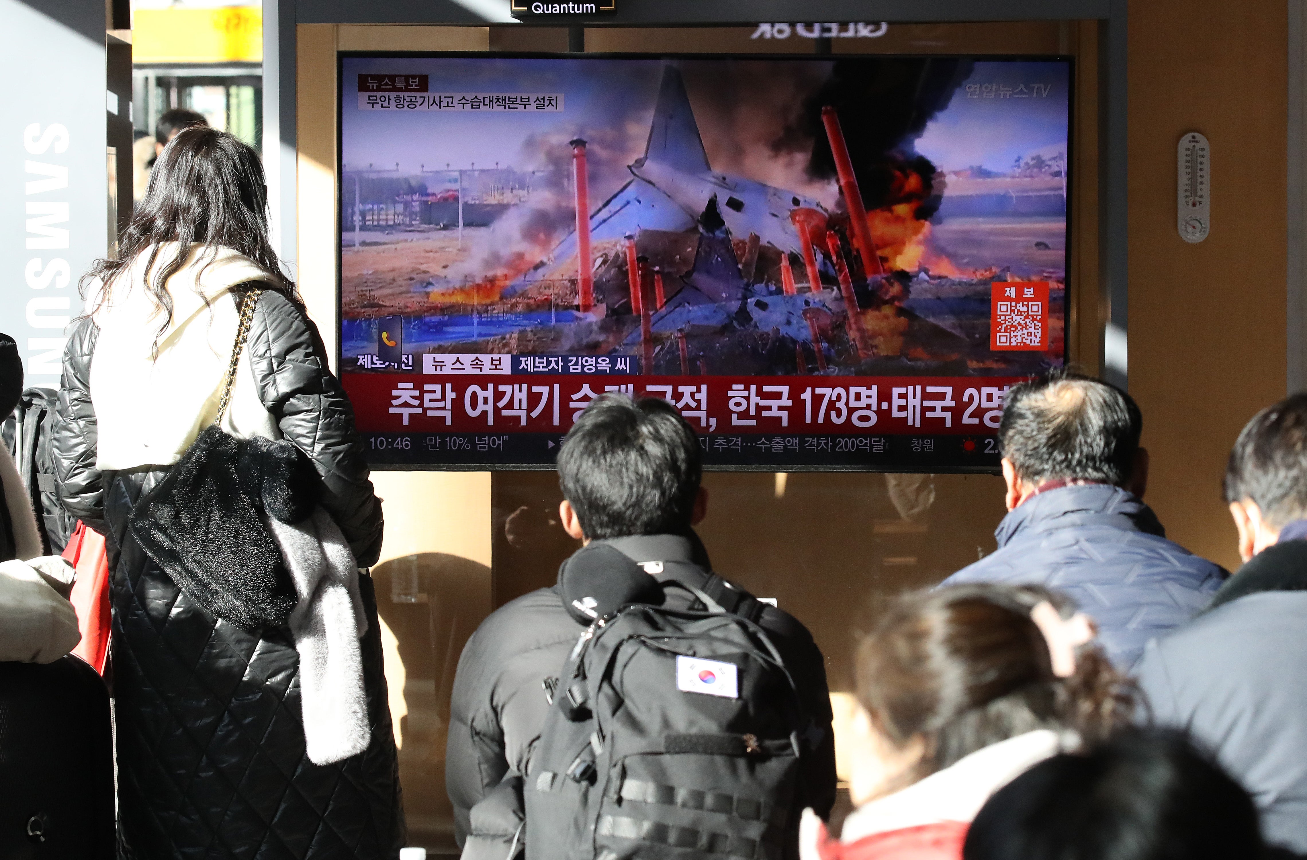 People watch the news regarding the plane crash at Seoul station