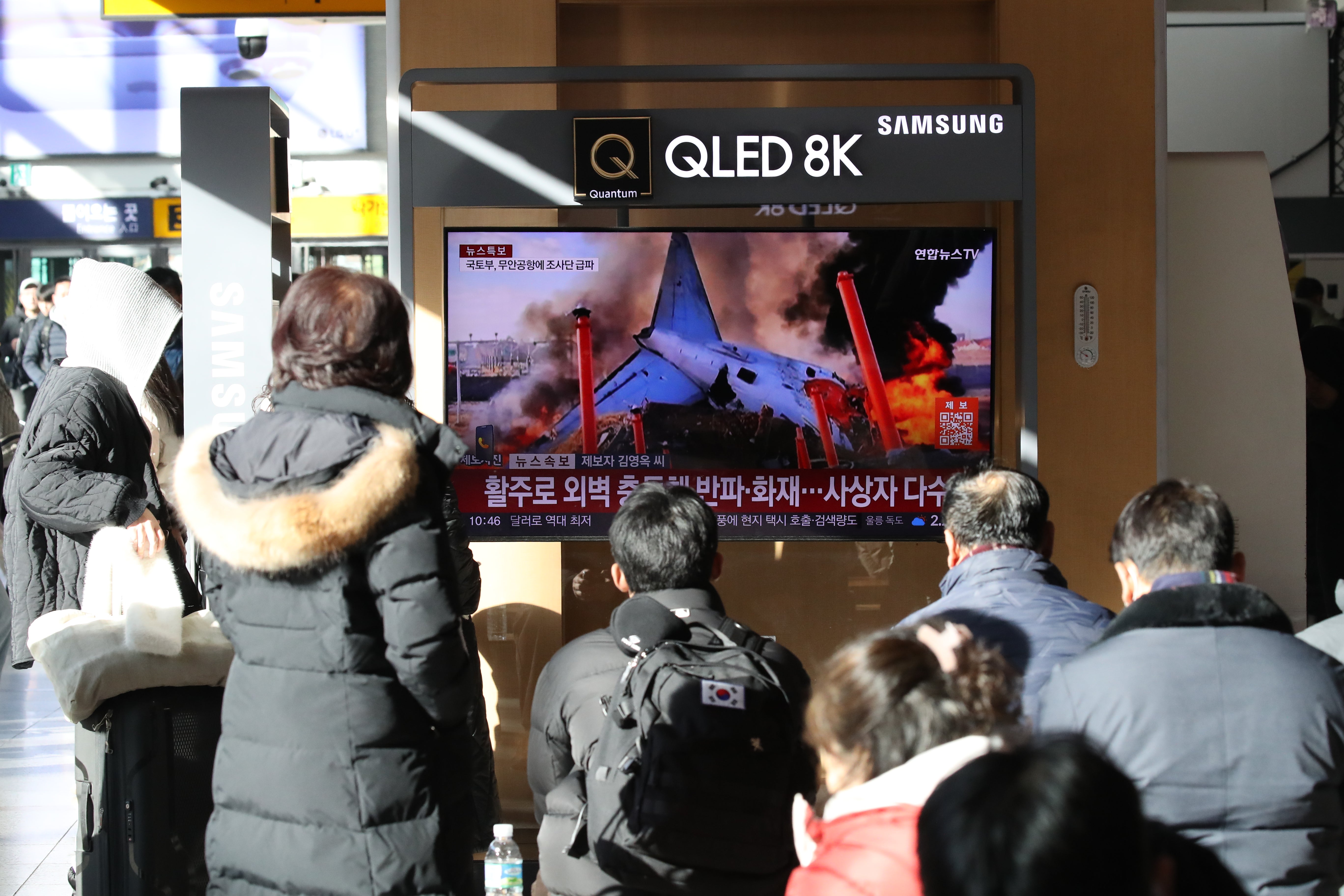 People watch the news regarding the plane crash at Seoul station