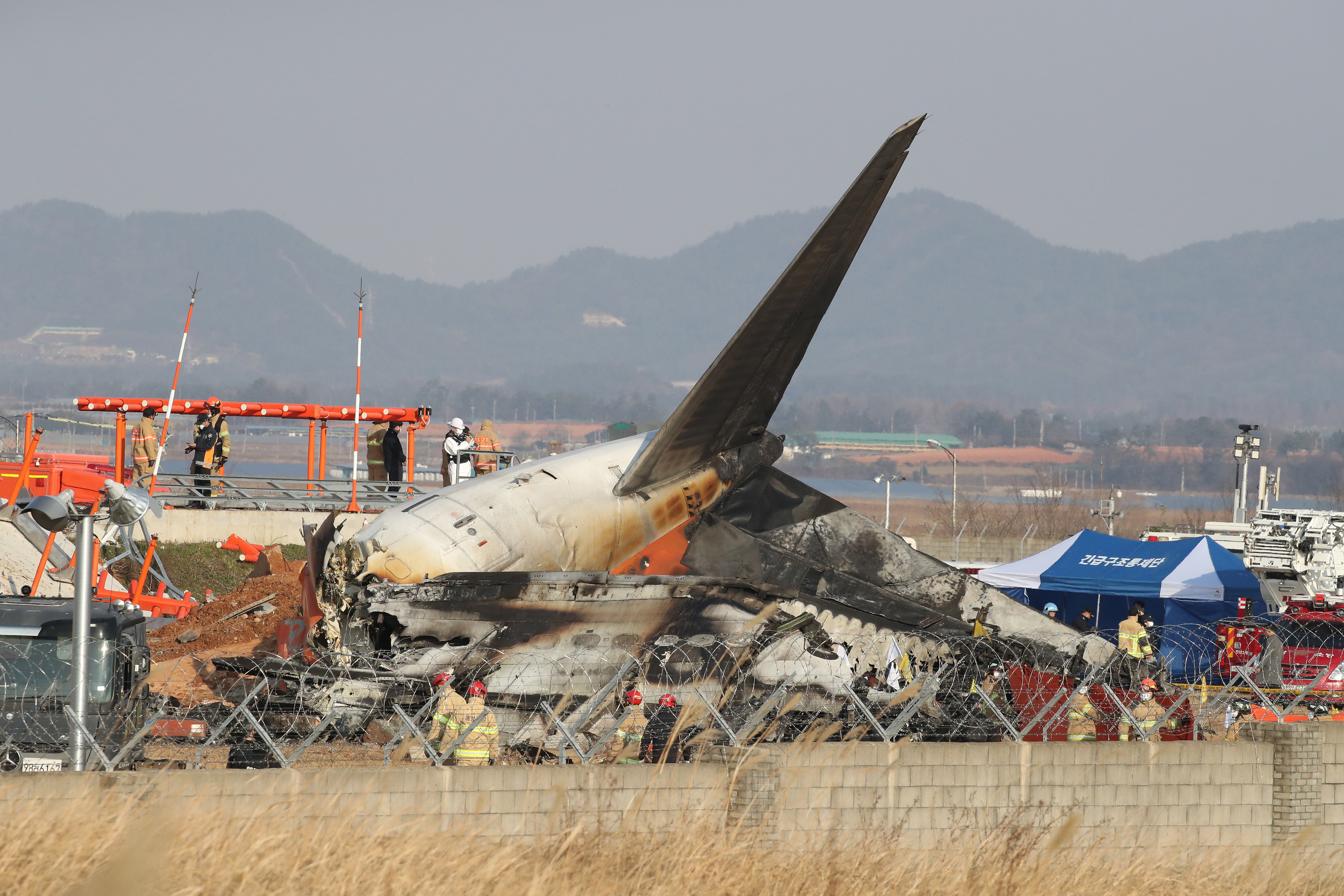 Firefighters and rescue team work at the wreckage of a passenger plane at Muan International Airport