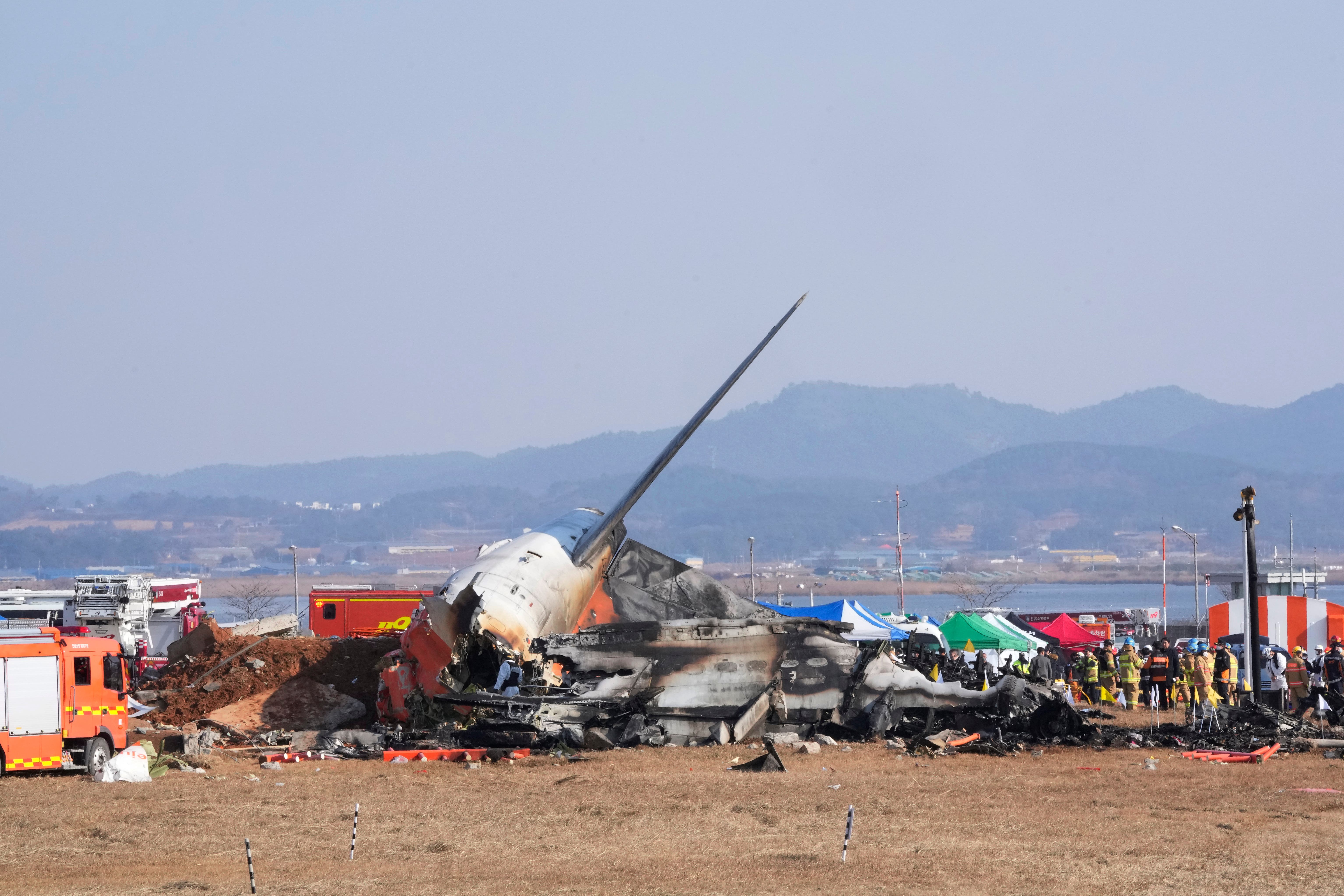 Firefighters and rescue team members work near the wreckage of the passenger plane (Ahn Young-joon/AP/PA)