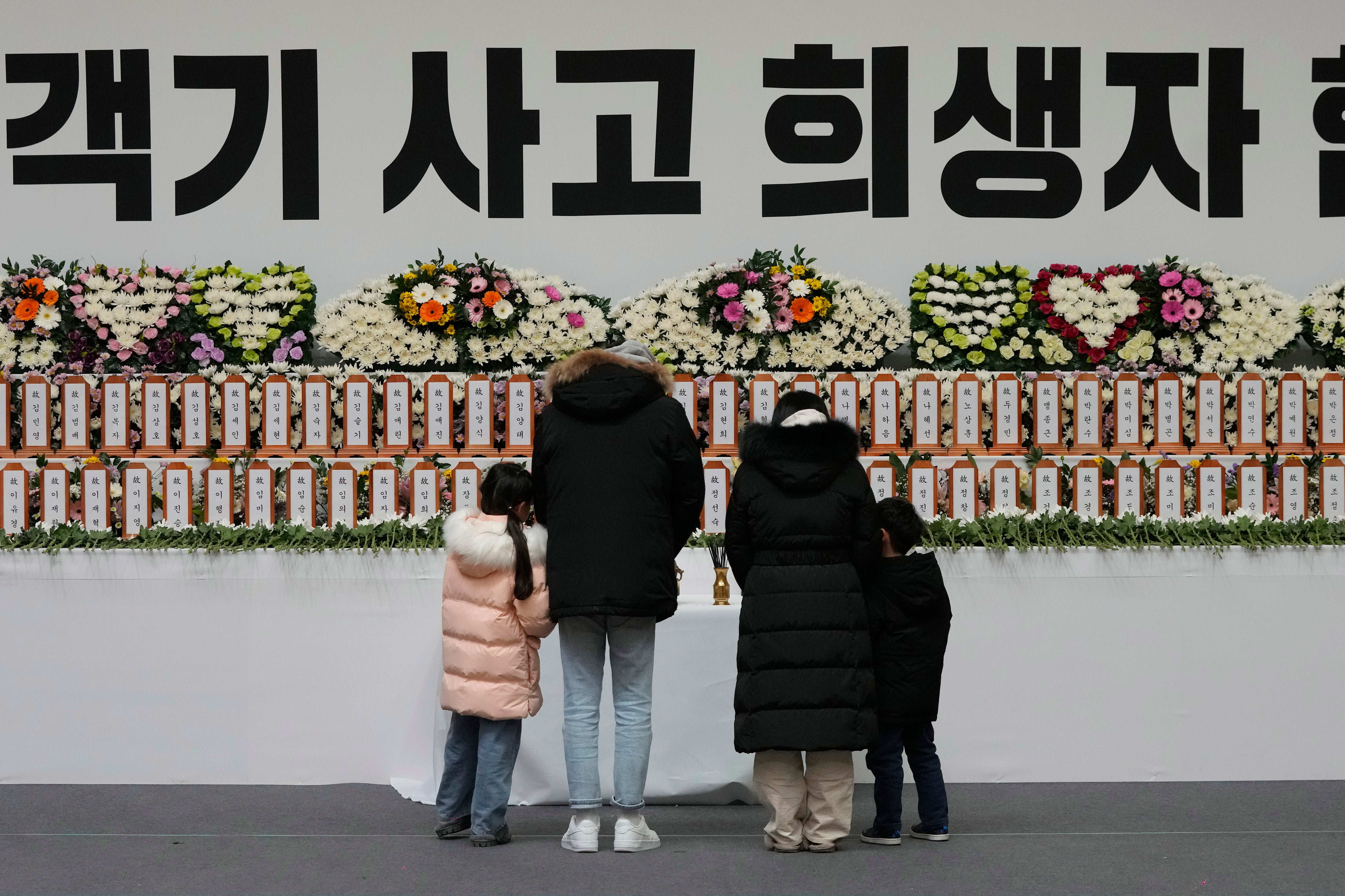 Mourners pray for the victims on a plane fire at a memorial