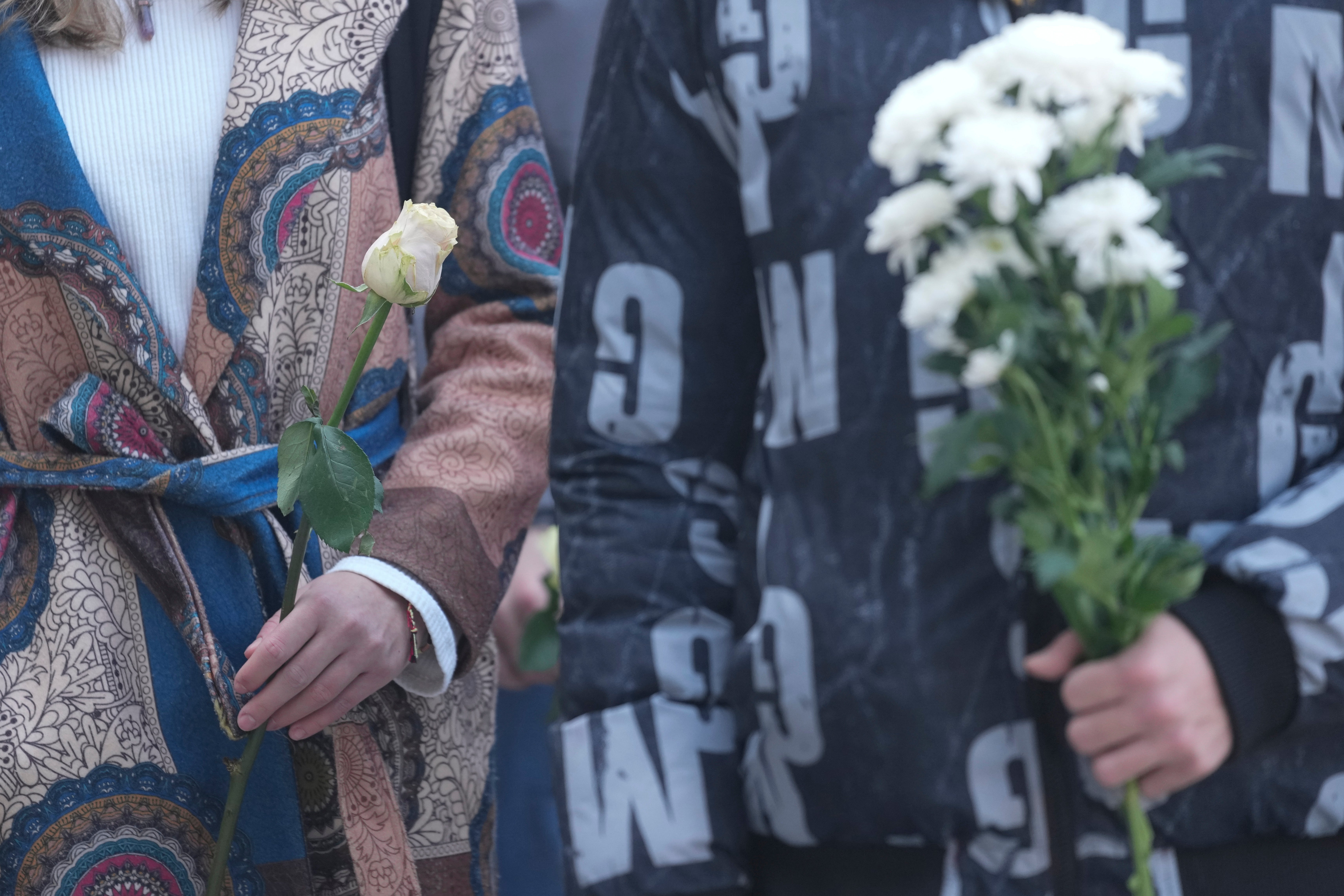 Students hold white flowers in front of the court building during a verdict