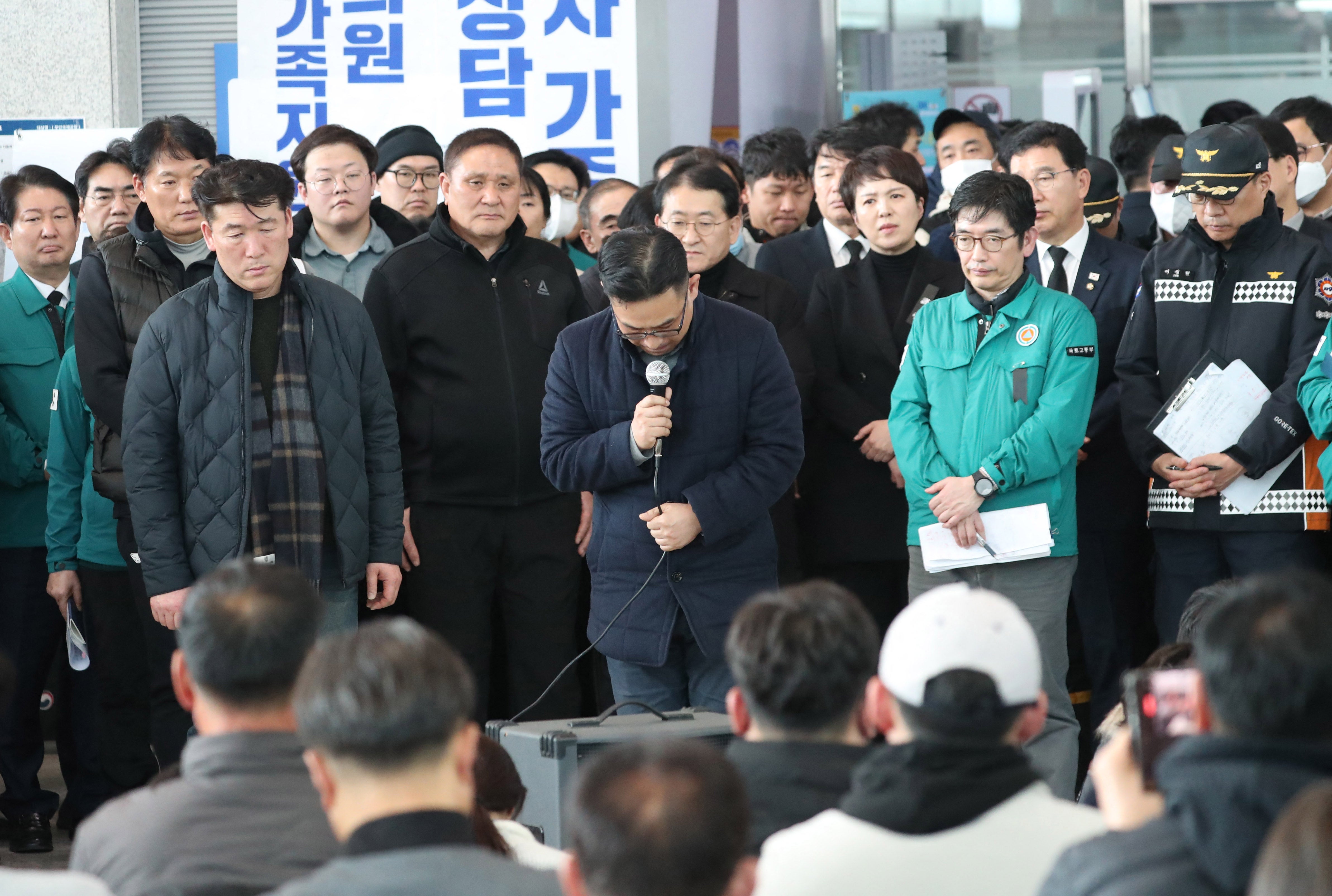 A Jeju Air official (C) bows his head and apologises to the bereaved families of passengers of the Jeju Air passenger plane.