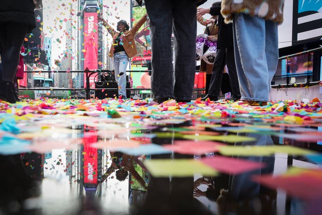 <p>People pose for photos as they throw confetti ahead of New Year’s Eve  in New York City’s Times Square. One million visitors are expected to mark the holiday there. They will face stormy weather, including thunder and lightning </p>