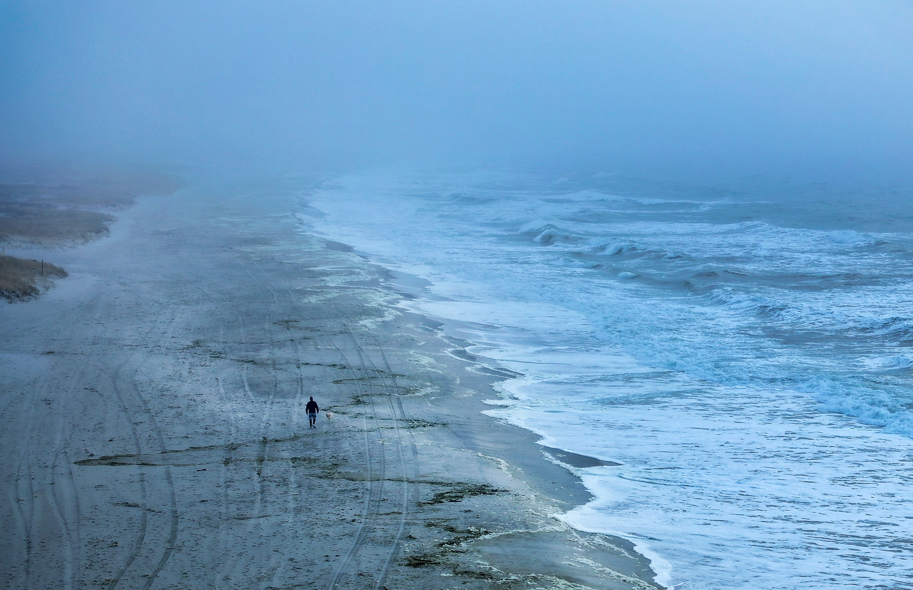 A man and dog walk on a beach in Hempstead, New York, on Monday. Temperatures will drop quickly across the eastern US