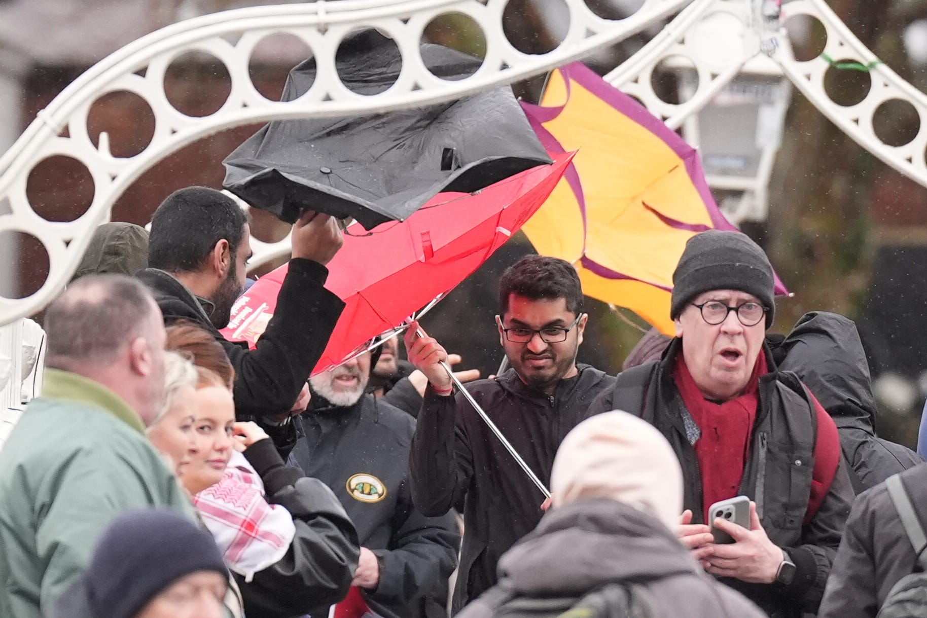 People struggle with their umbrellas as the wind picks up in Dublin’s city centre, as snow, rain and wind warnings are in force and are expected to cause travel issues on New Year’s Eve (Niall Carson/PA)