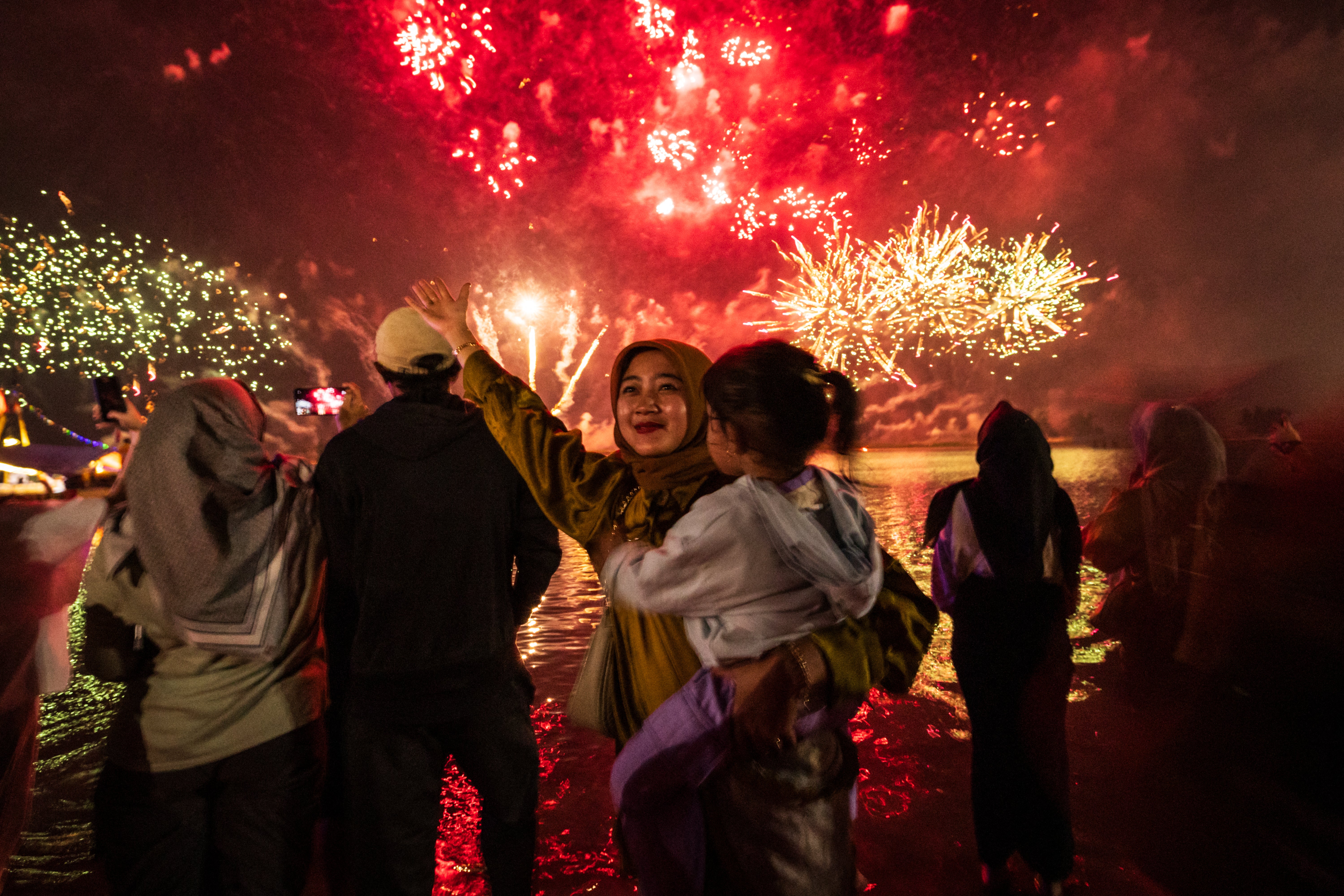 Local residents look at fireworks as they celebrate the New Year at Ancol Beach in Jakarta