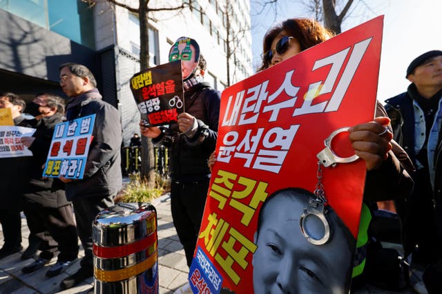 <p>A protester holds a banner saying ‘Arrest rebellion leader Yoon Suk Yeol right now’ outside the president’s official residence in Seoul, South Korea, on 31 December 2024</p>