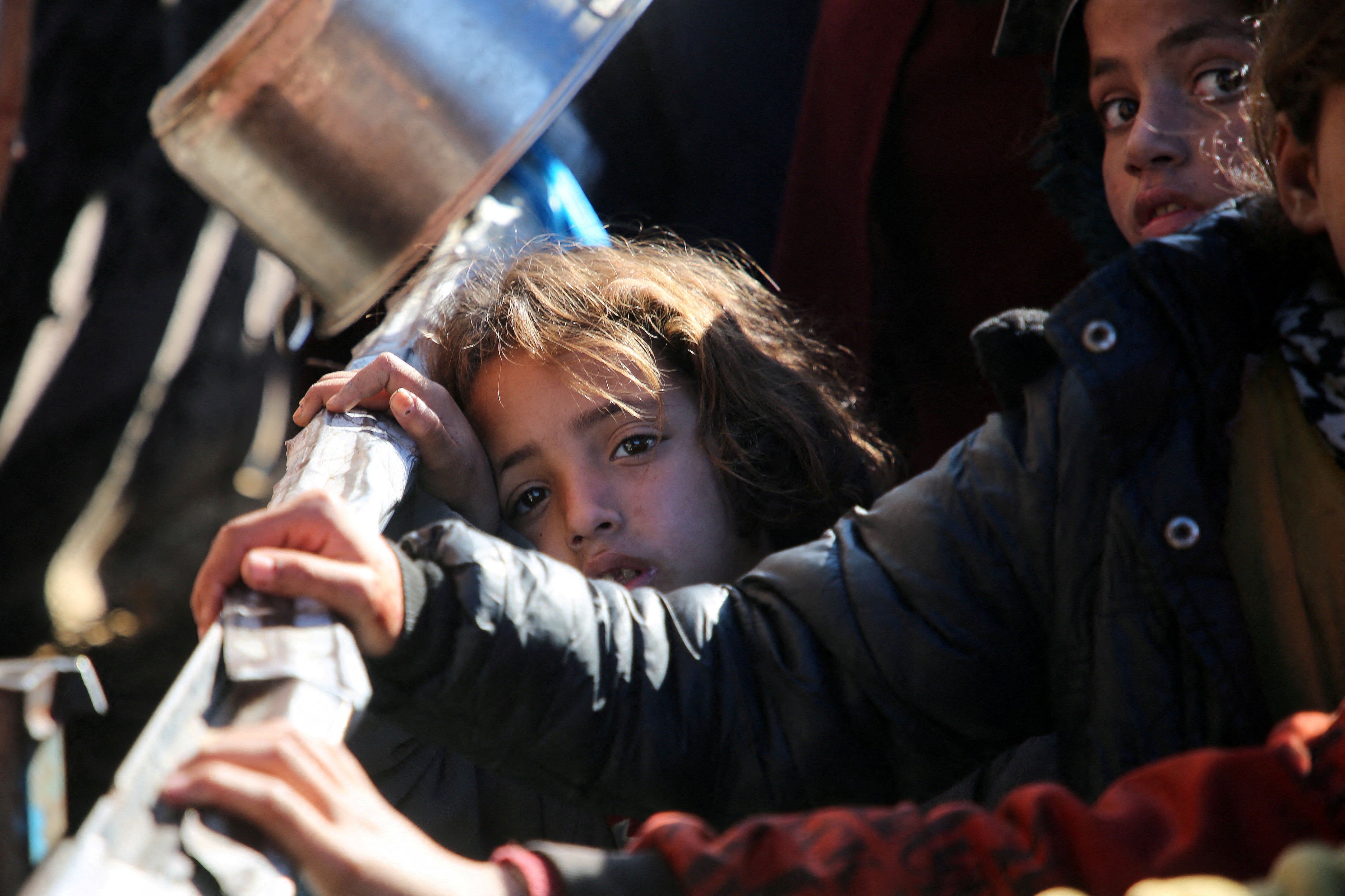 Palestinians gather to receive food cooked by a charity kitchen, in Khan Younis