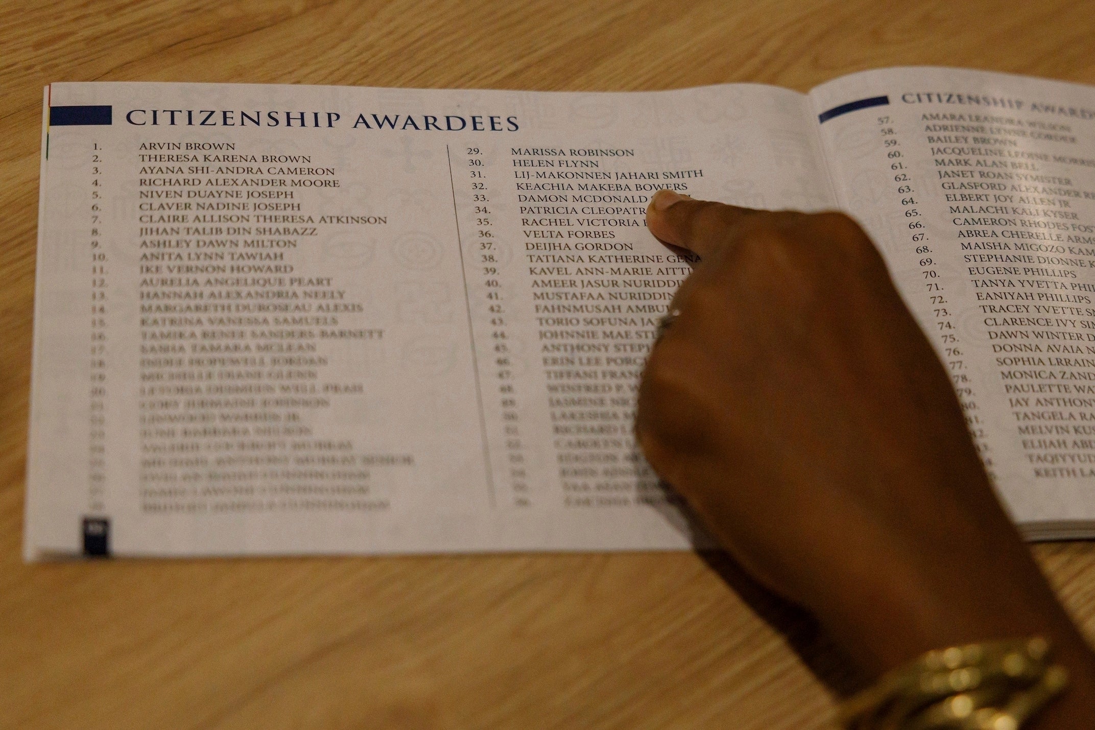 Keachia Bowers points to her name in a booklet listing people who are part of the Black diaspora