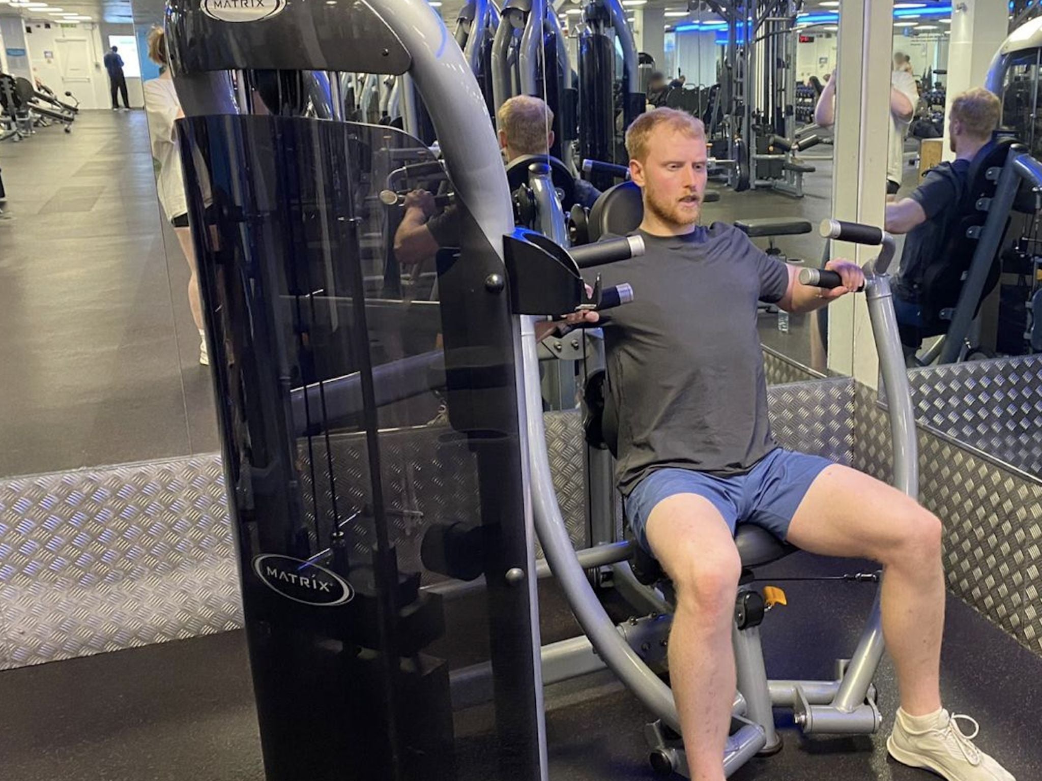 Performing a chest press using a machine at The Gym Group