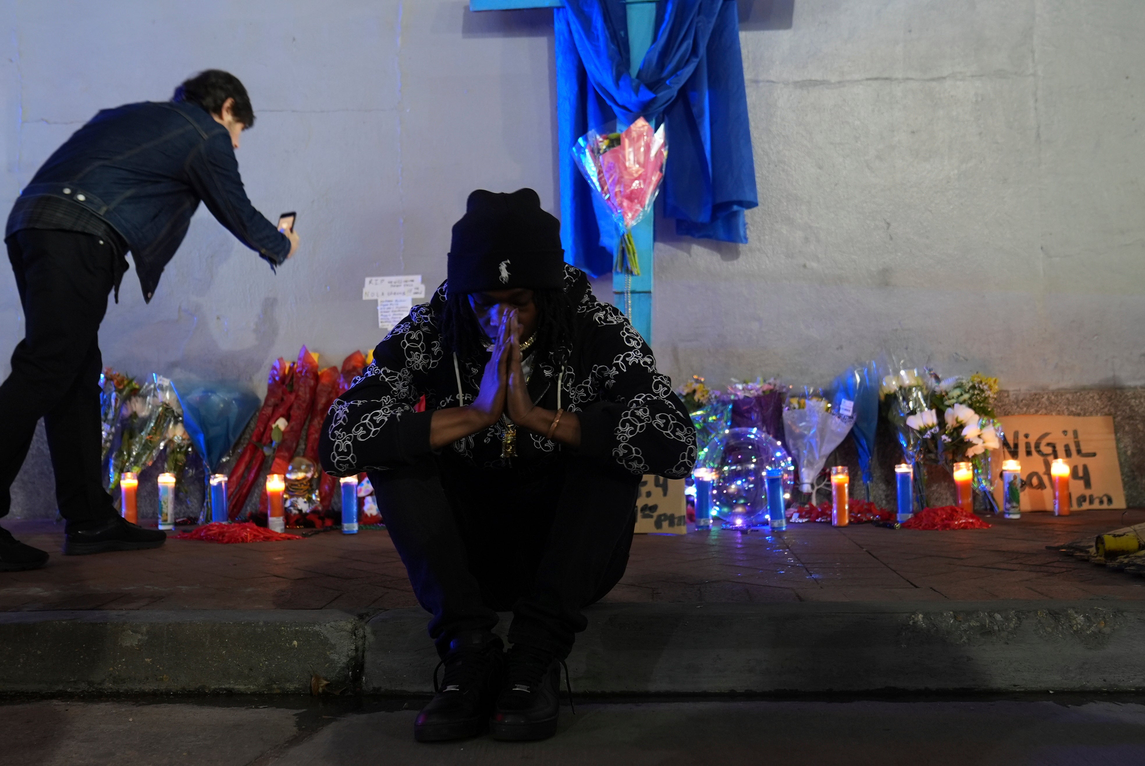 Sav Bennly sits in front of a memorial at Bourbon and Canal Street in the French Quarter on Thursday