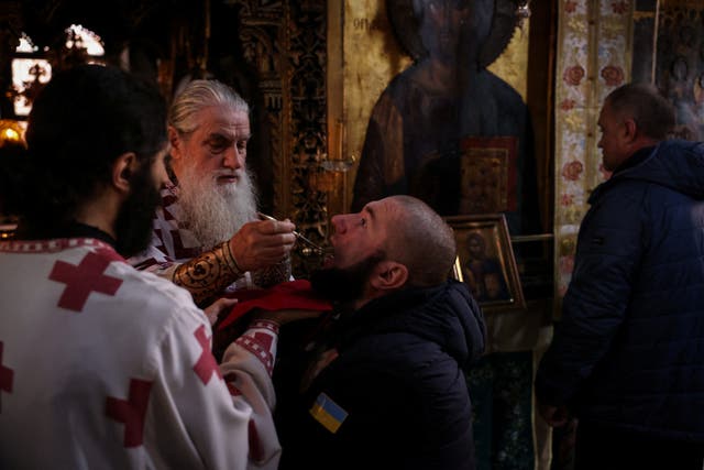 <p>Military intelligence officer Volodymyr Yakhtorovych, 41, receives the Holy Communion from Father Epifaneios, during a service at the church of the Pantokratoros Monastery in Mount Athos</p>