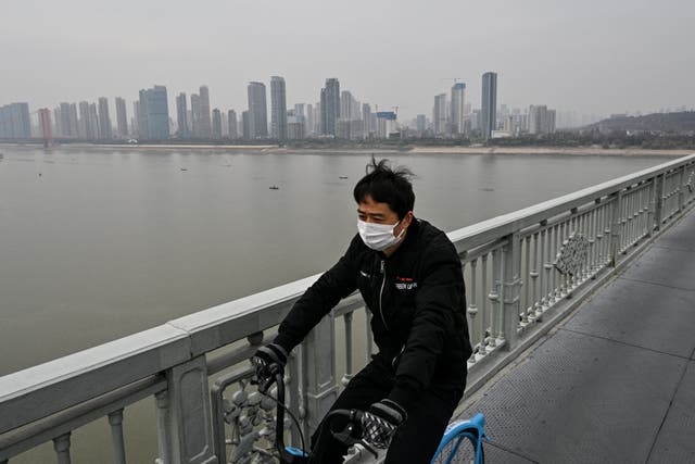 <p>Imagen de archivo: Un hombre monta en bicicleta sobre el puente de Wuhan que cruza el río Yangtsé, en la ciudad de Wuhan, provincia central de Hubei, China, el 22 de diciembre de 2024. La escena tiene lugar días antes del quinto aniversario de la confirmación de la primera muerte por el covid-19 reportada por las autoridades chinas</p>