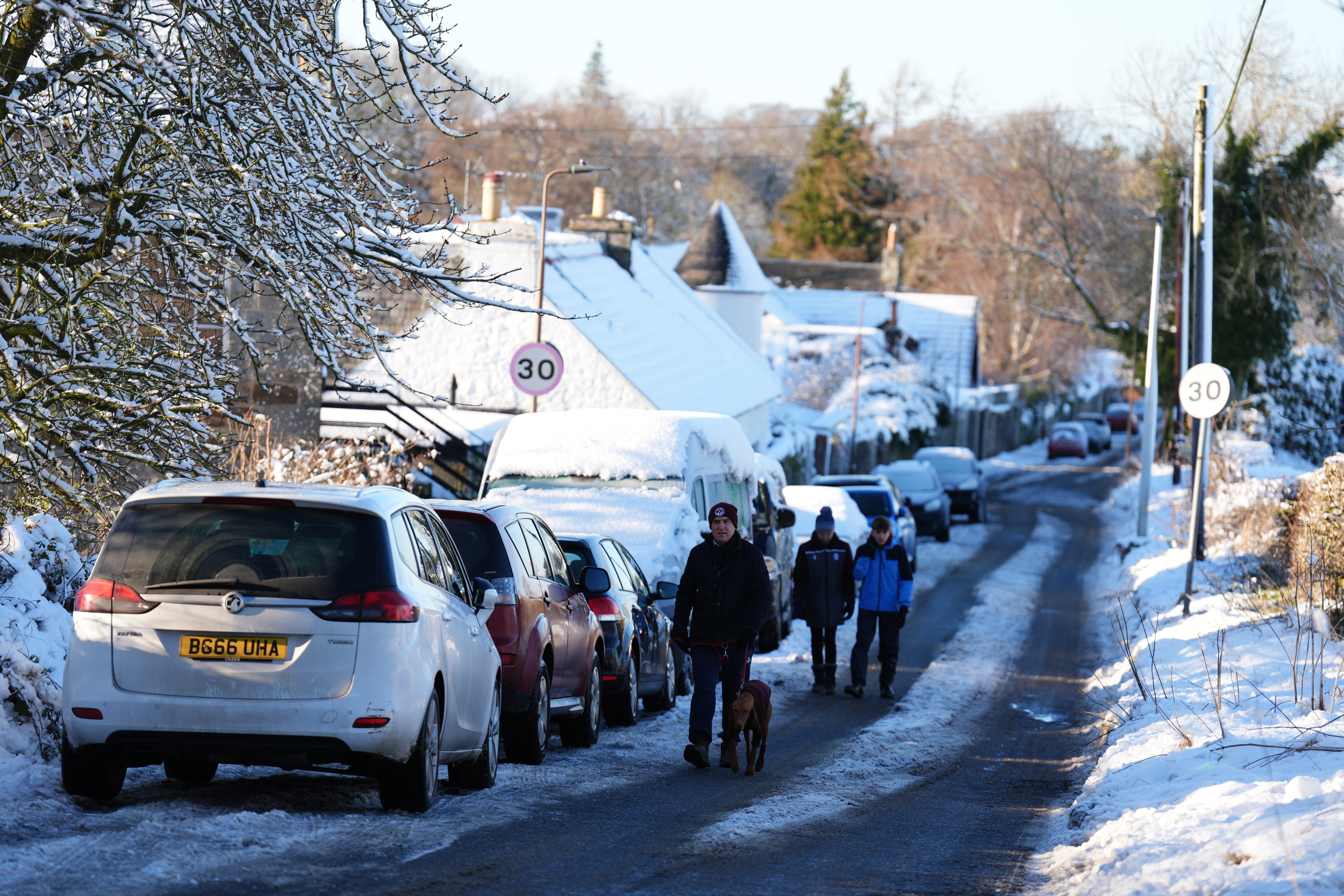 People walk through snow in Balerno, Edinburgh, on Friday