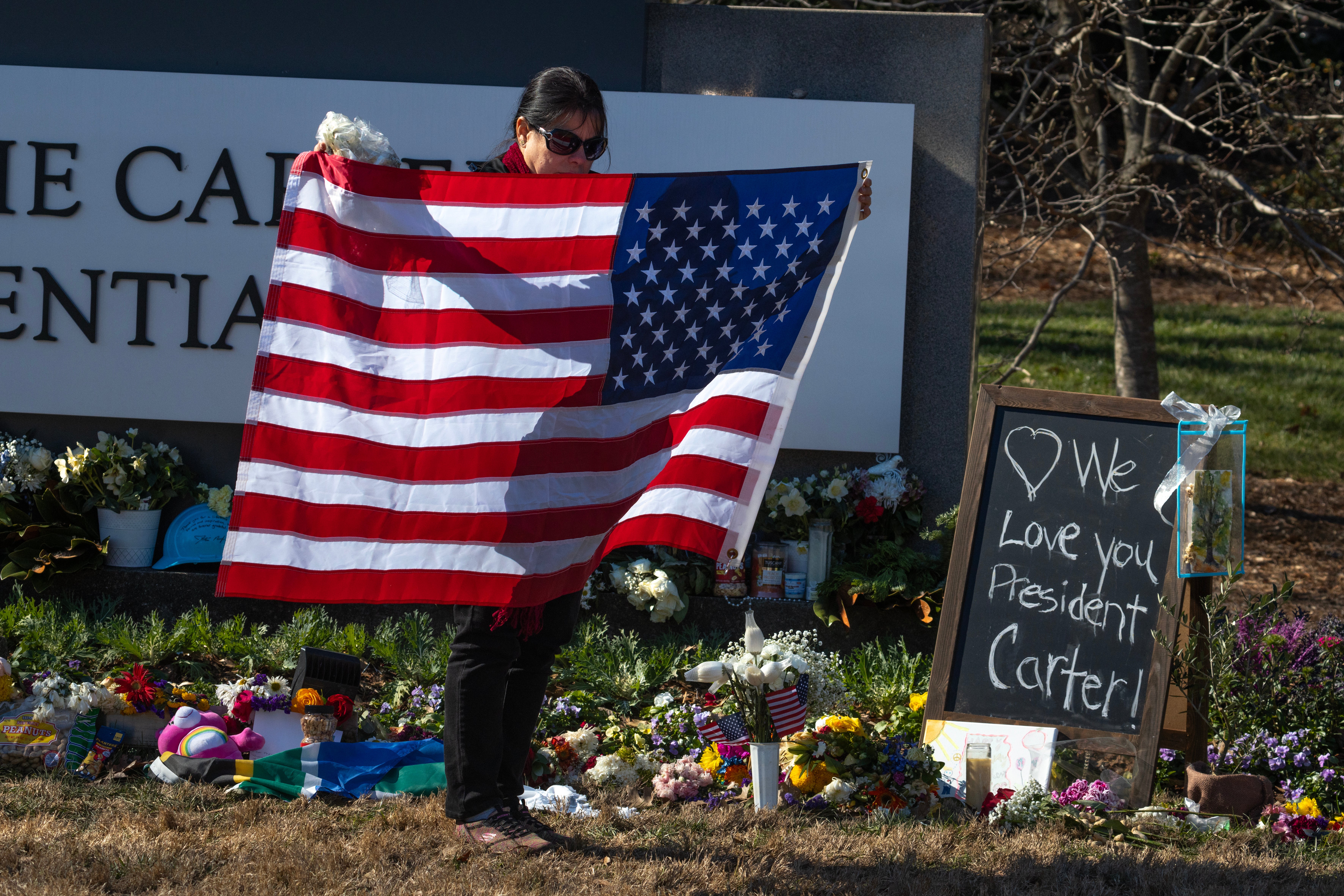 A mourner holds a flag outside of the Carter Center in Atlanta, Georgia on Saturday afternoon