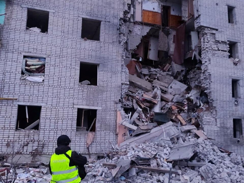 A police officer stands in a front of a residential building hit by a Russian air strike