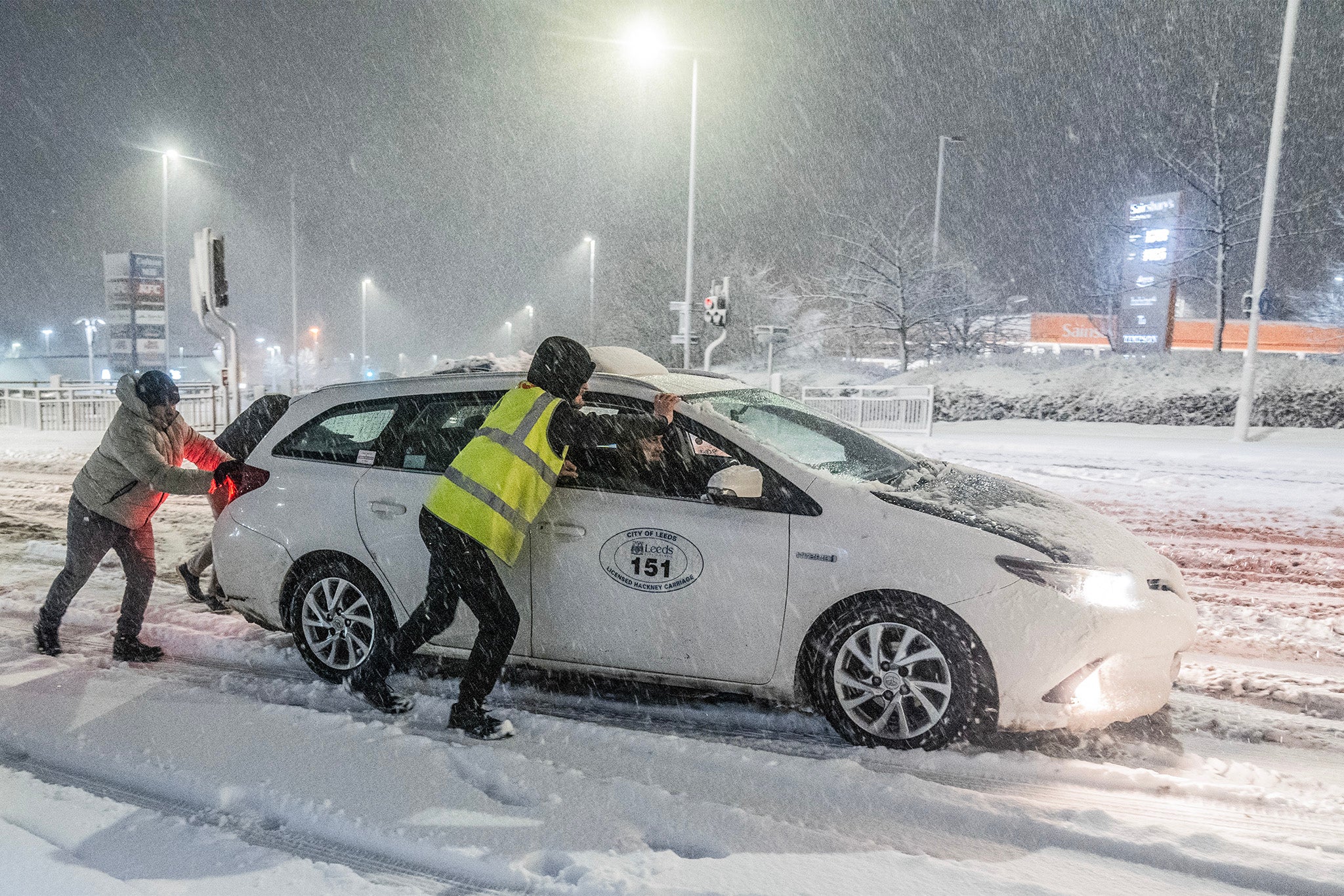 People help to push cars stuck in snow in Leeds