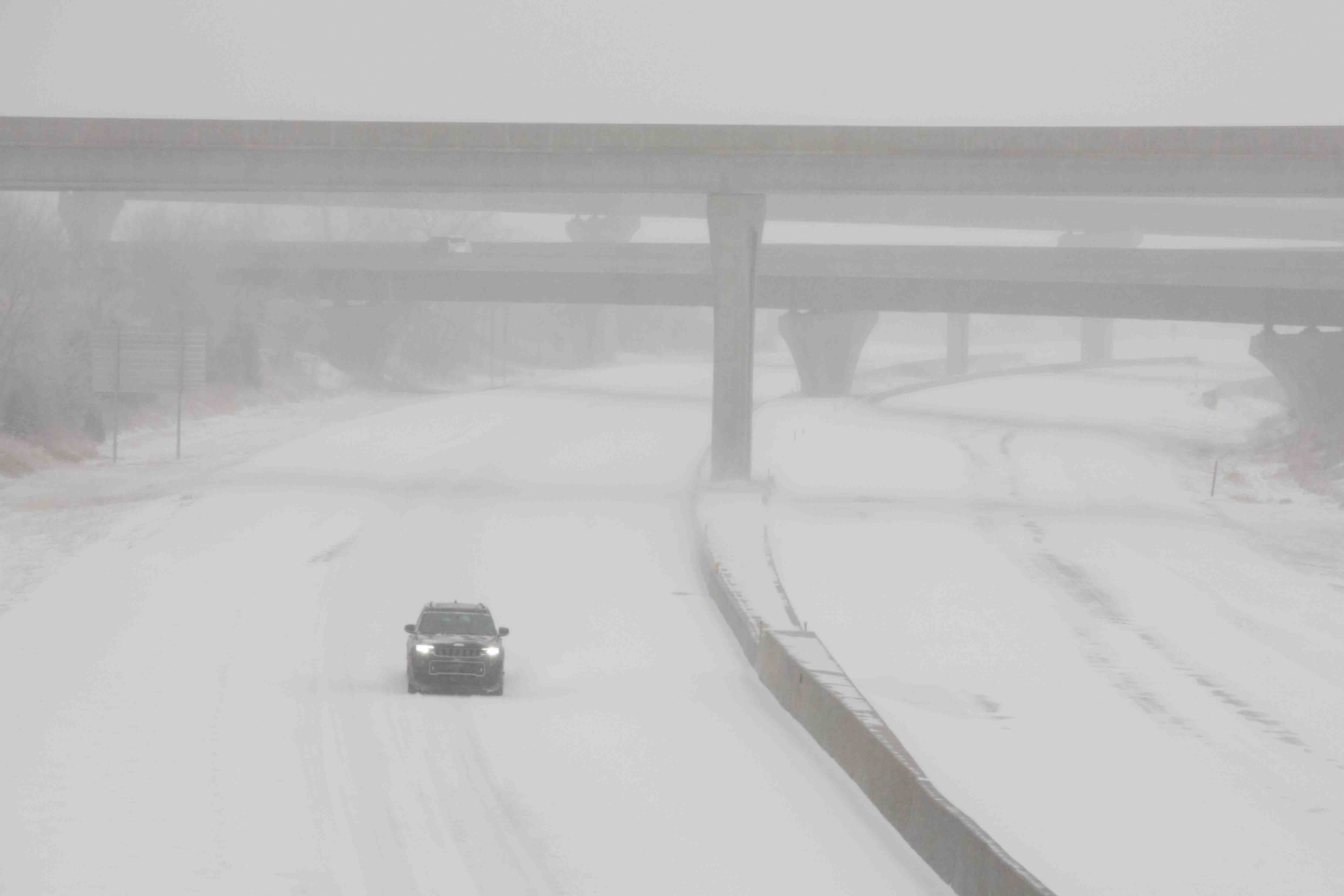 A car drives on Interstate 70 amid heavy snowfall in Topeka, Kansas on Sunday morning