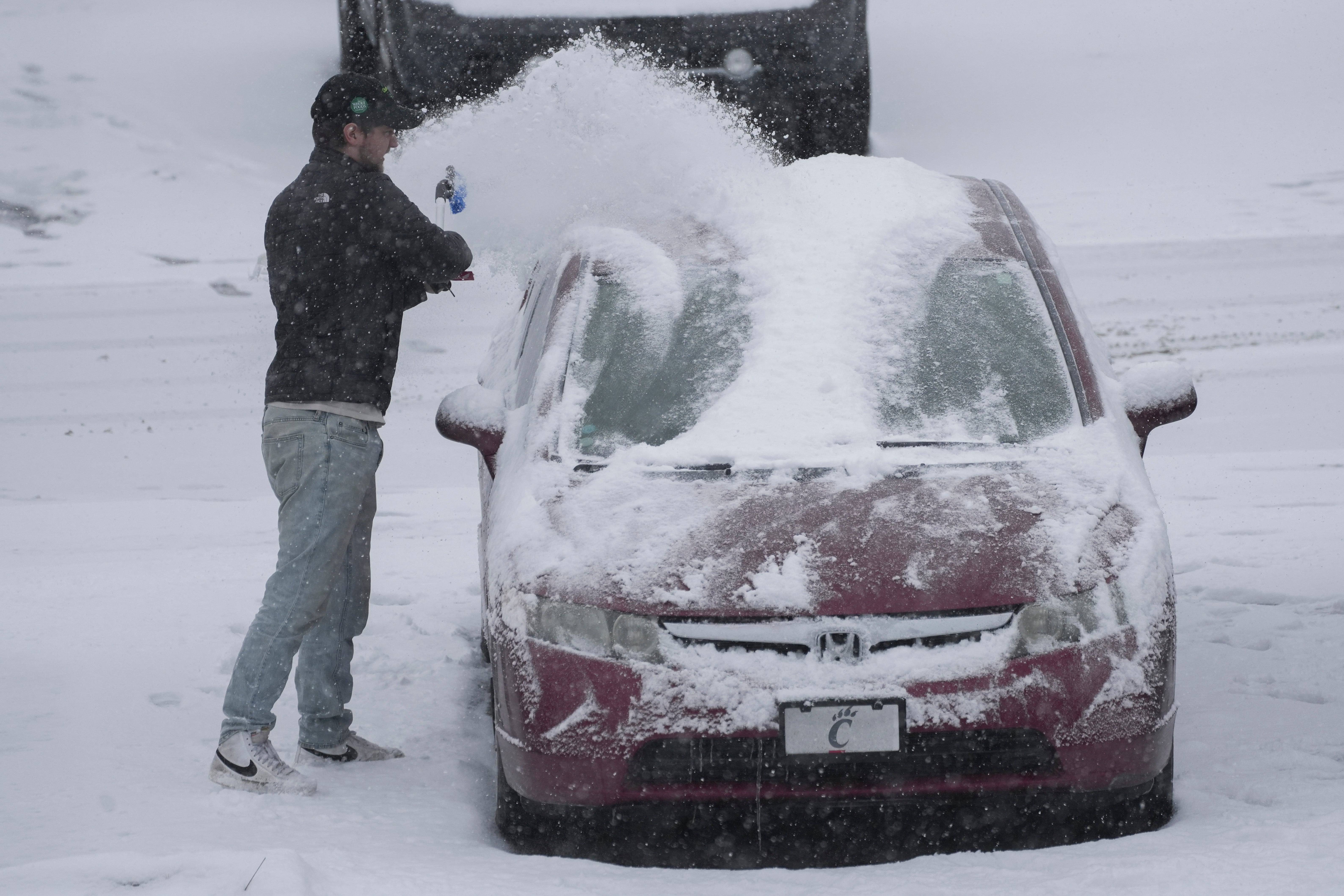 A Cincinnati resident brushes snow off his car on Sunday. The winter storm will reach the mid-Atlantic late Sunday or early Monday after passing through the Ohio River Valley