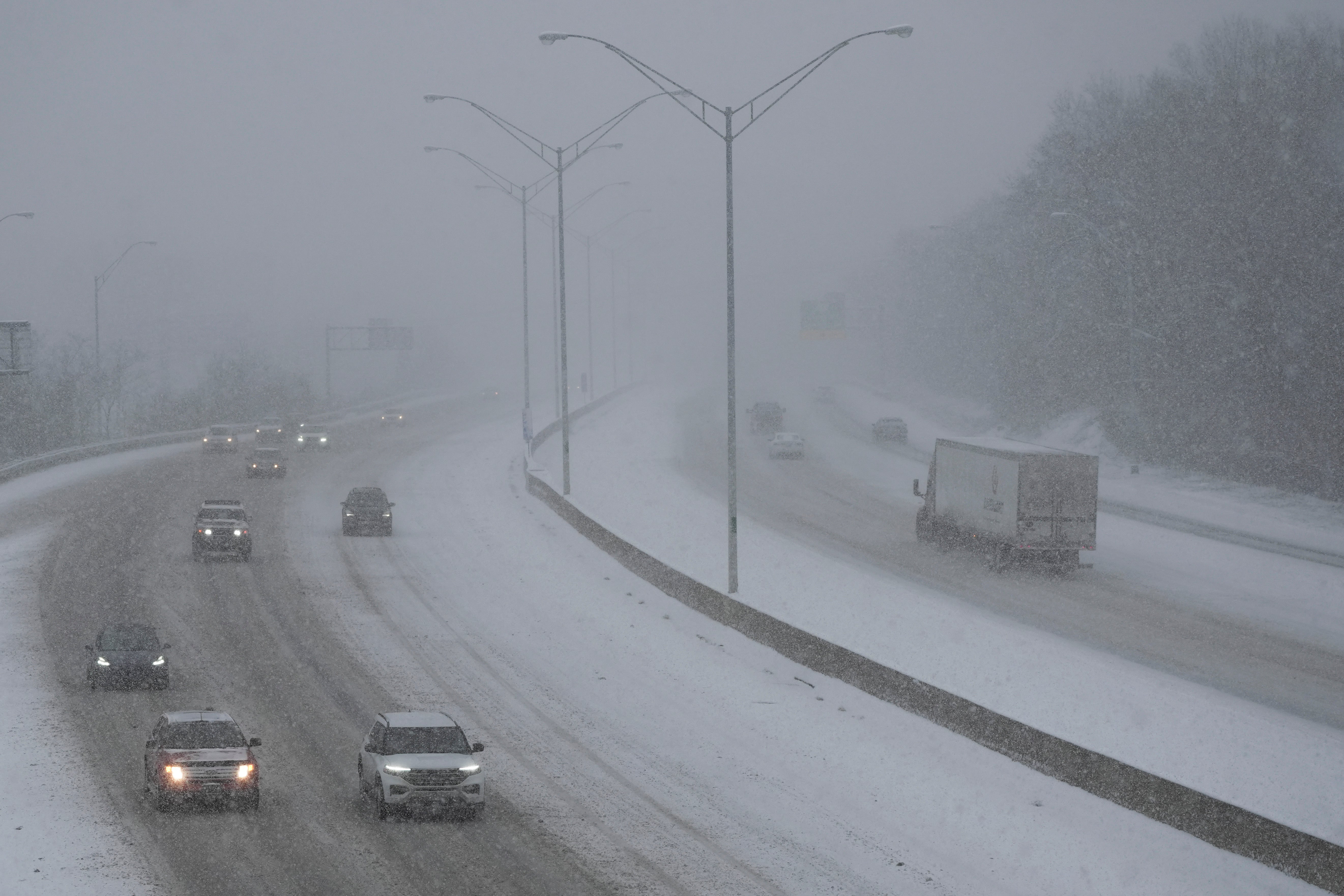 Cars drive on a highway in Cincinnati as snow falls on Sunday