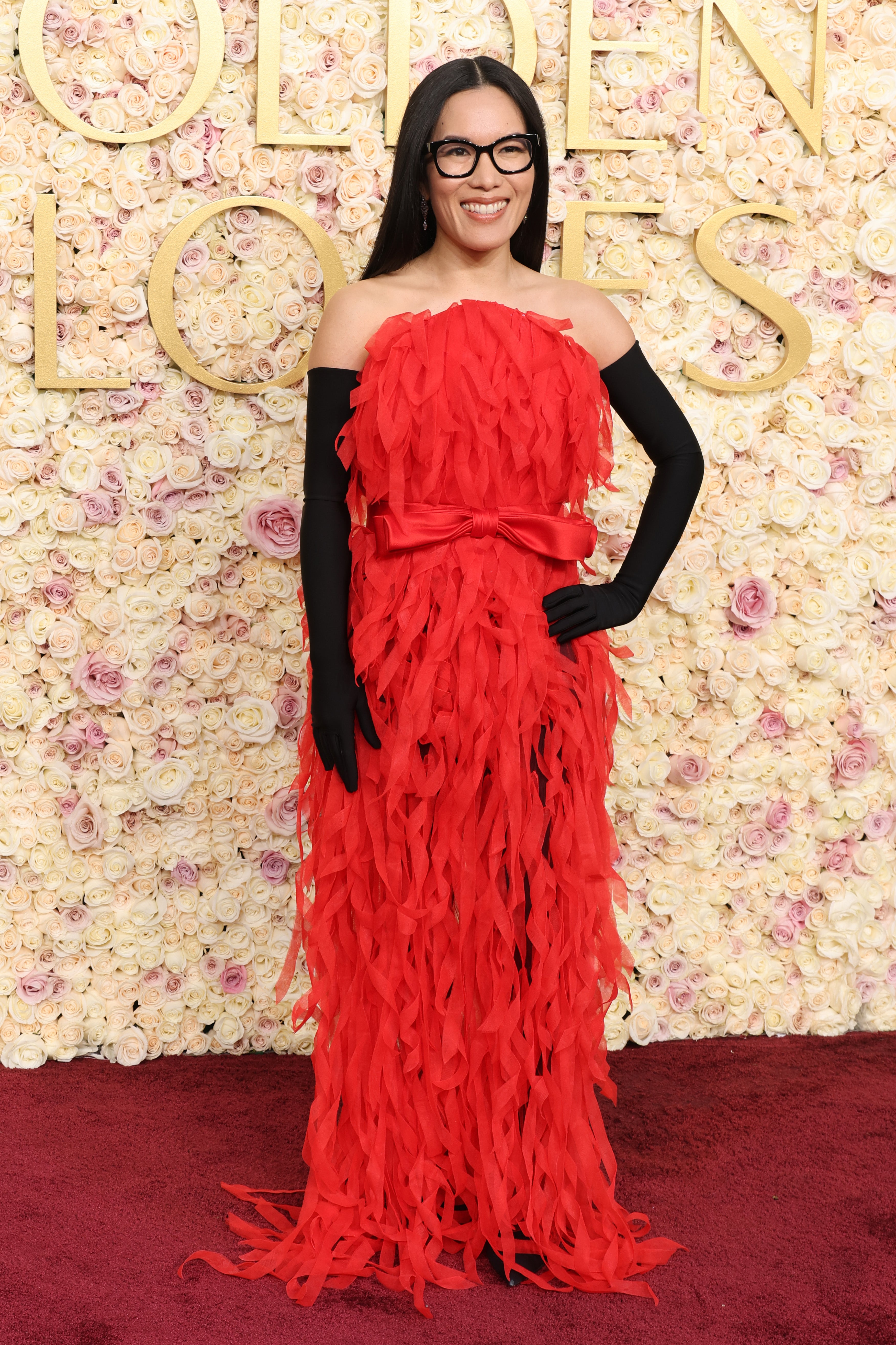 Ali Wong wears an elegant red gown with opera gloves on the Golden Globes red carpet