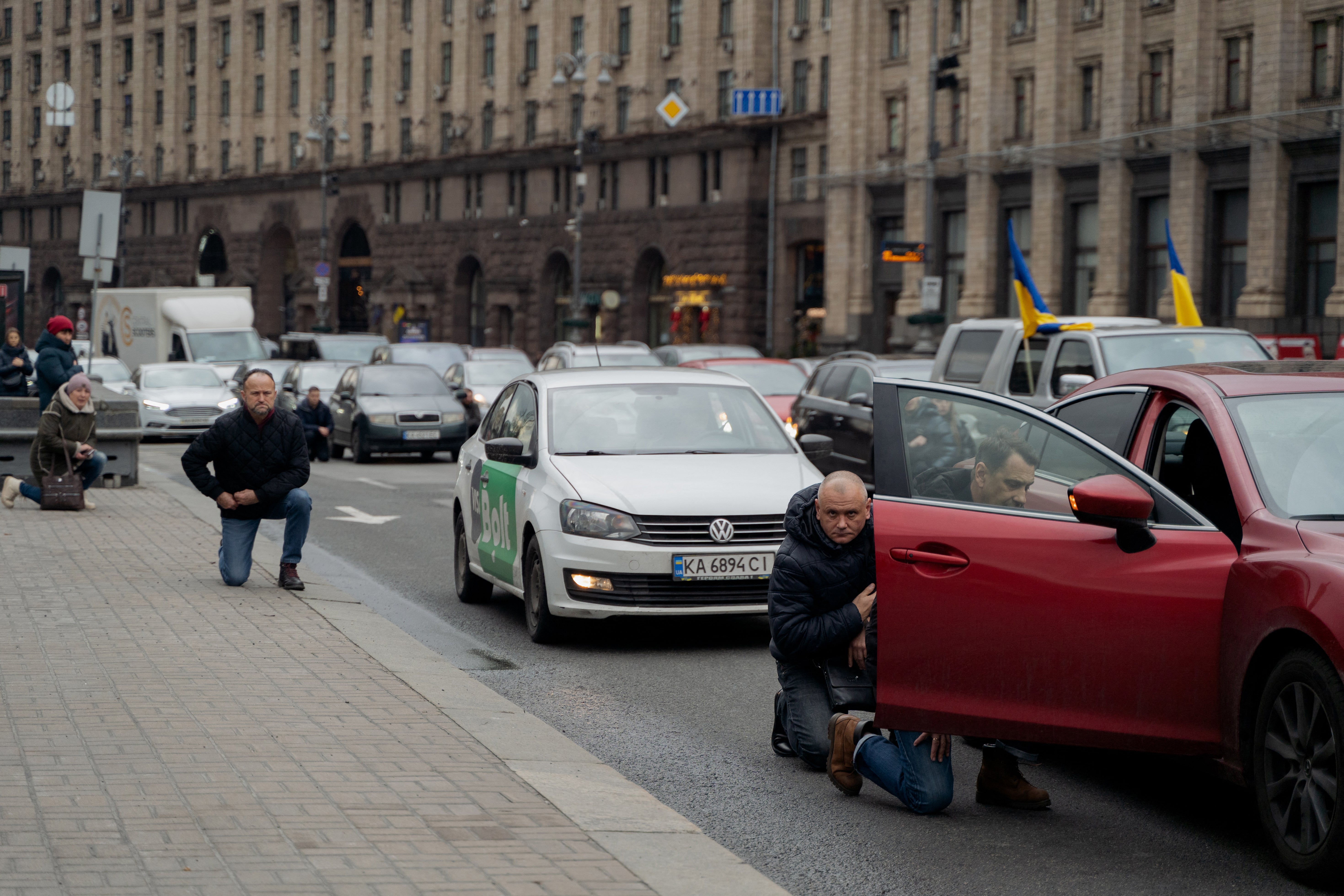 People kneel to honour a fallen Ukranian soldier during a funeral procession at the Independence Square in Kyiv