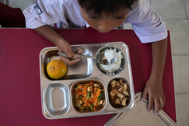 <p>A student eating during President Prabowo Subianto's ambitious free meal program</p>