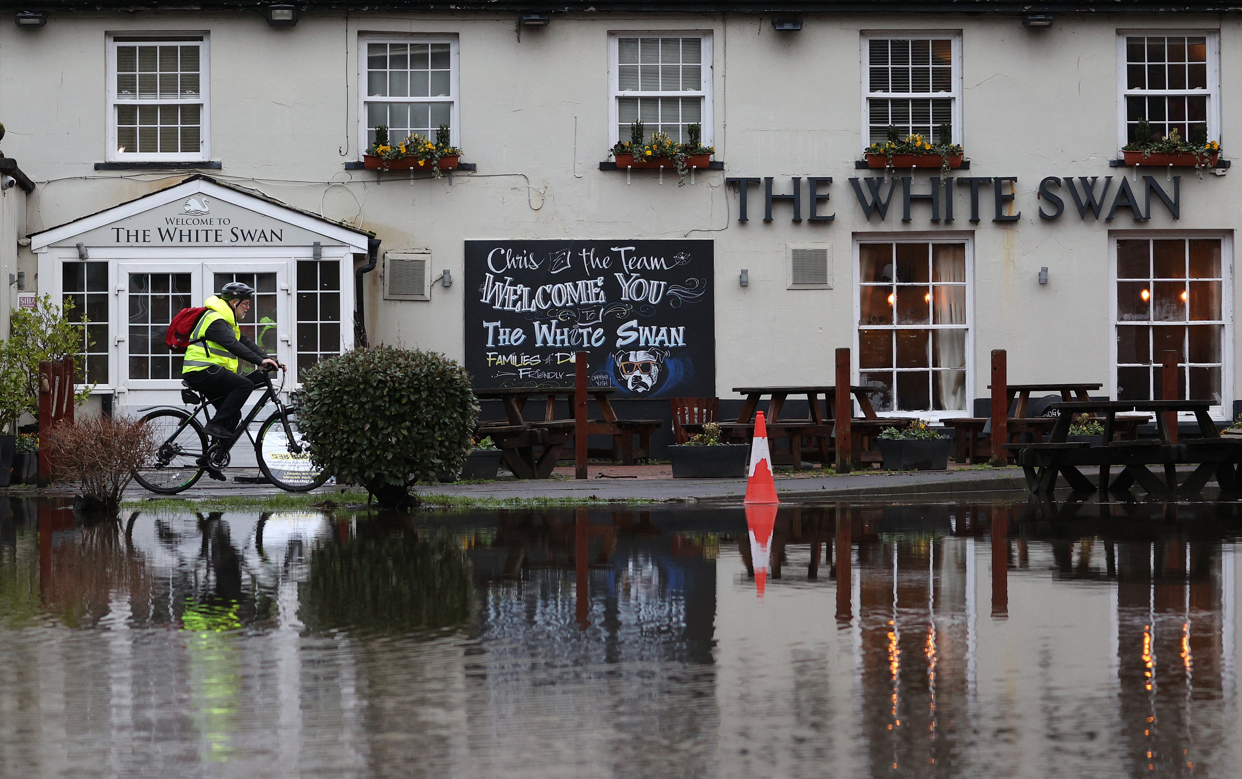 A cyclist rides a bike past the flooded car park of the White Swan after the River Itchen burst its banks following torrential rain, near Eastleigh, southern England