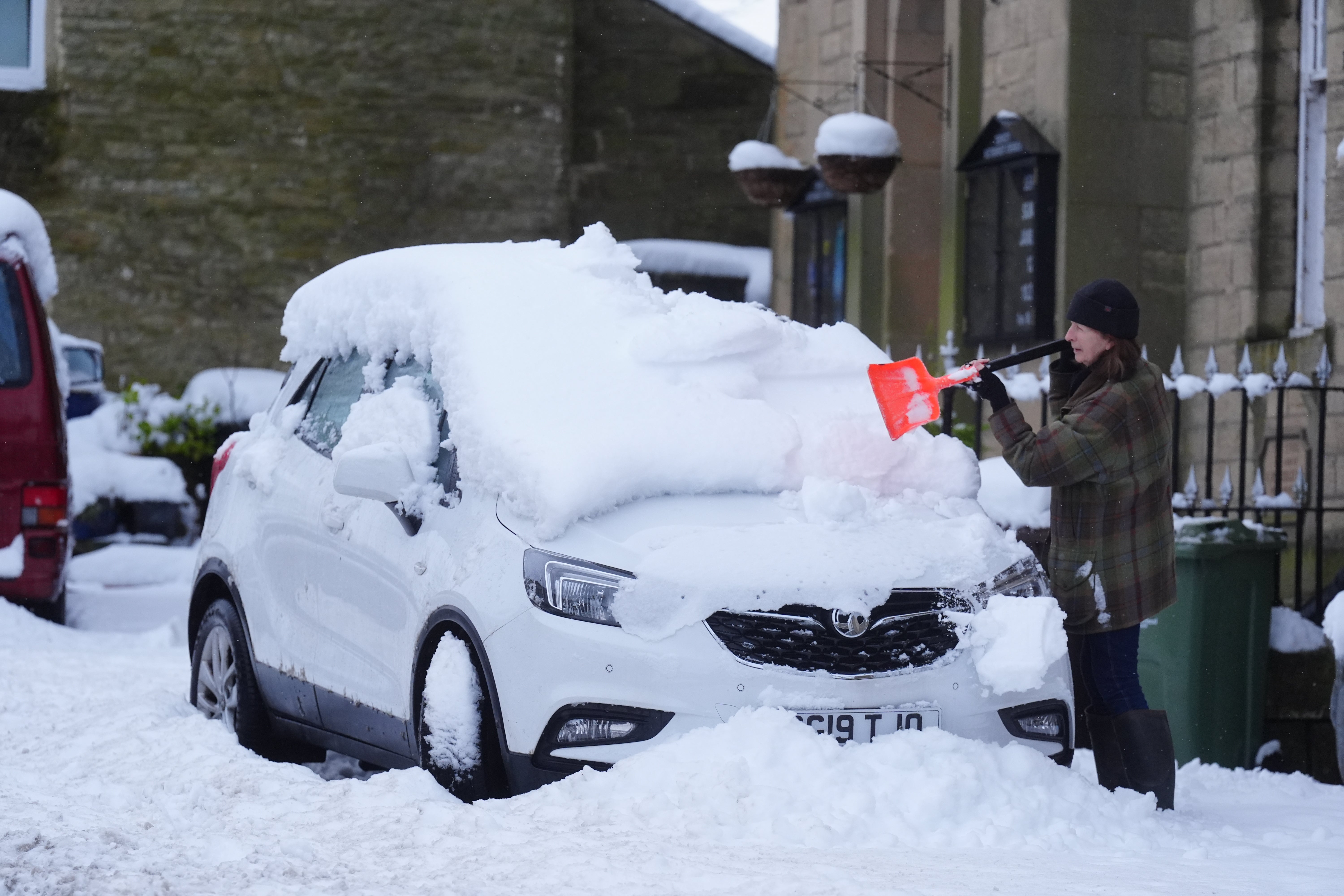 A person clears snow from a car in Allendale, Northumberland, on Monday