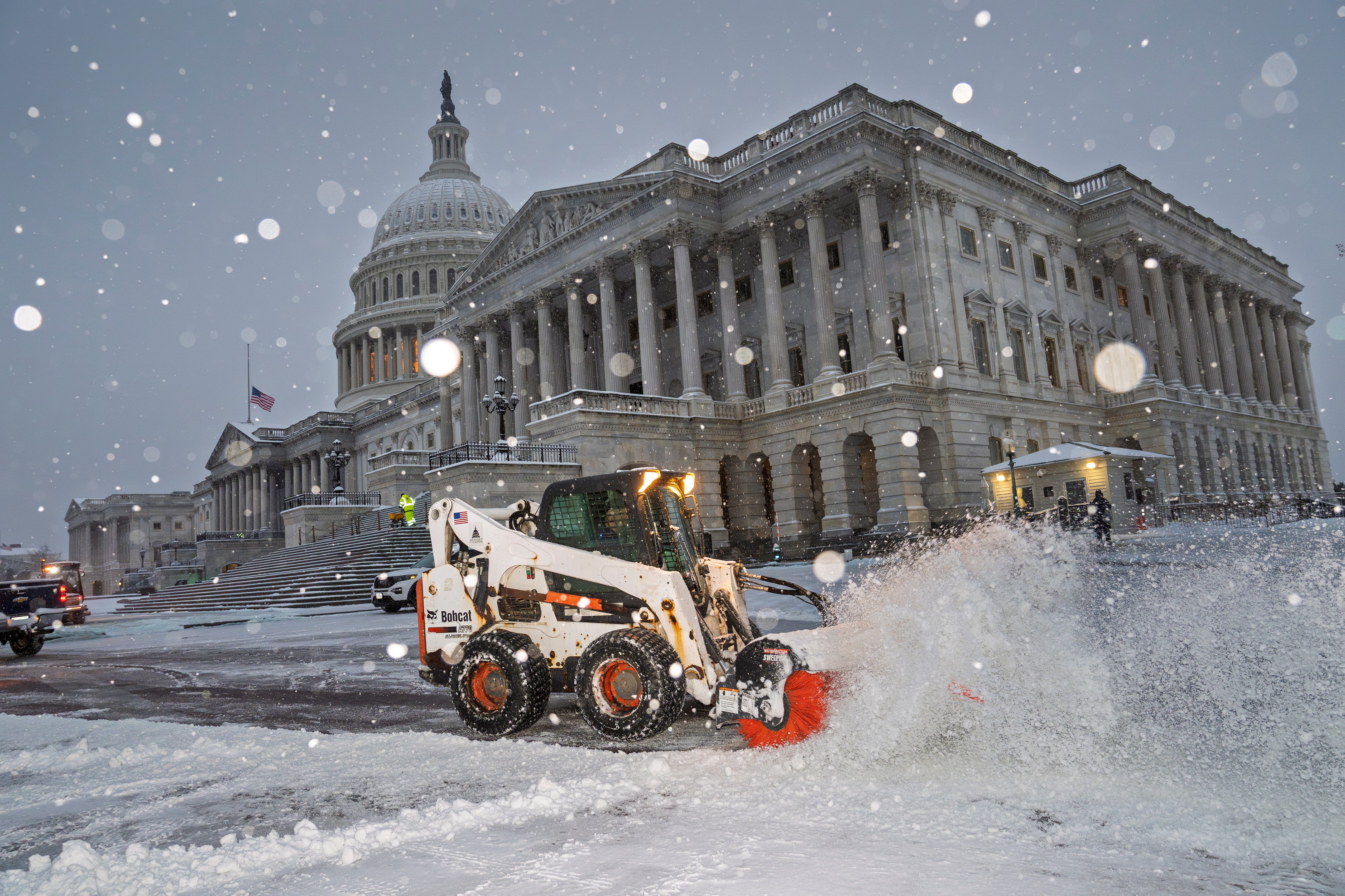 Workers clear the plaza at the Capitol as snow falls ahead of a joint session of Congress to certify the votes from the Electoral College in the 2024 presidential election