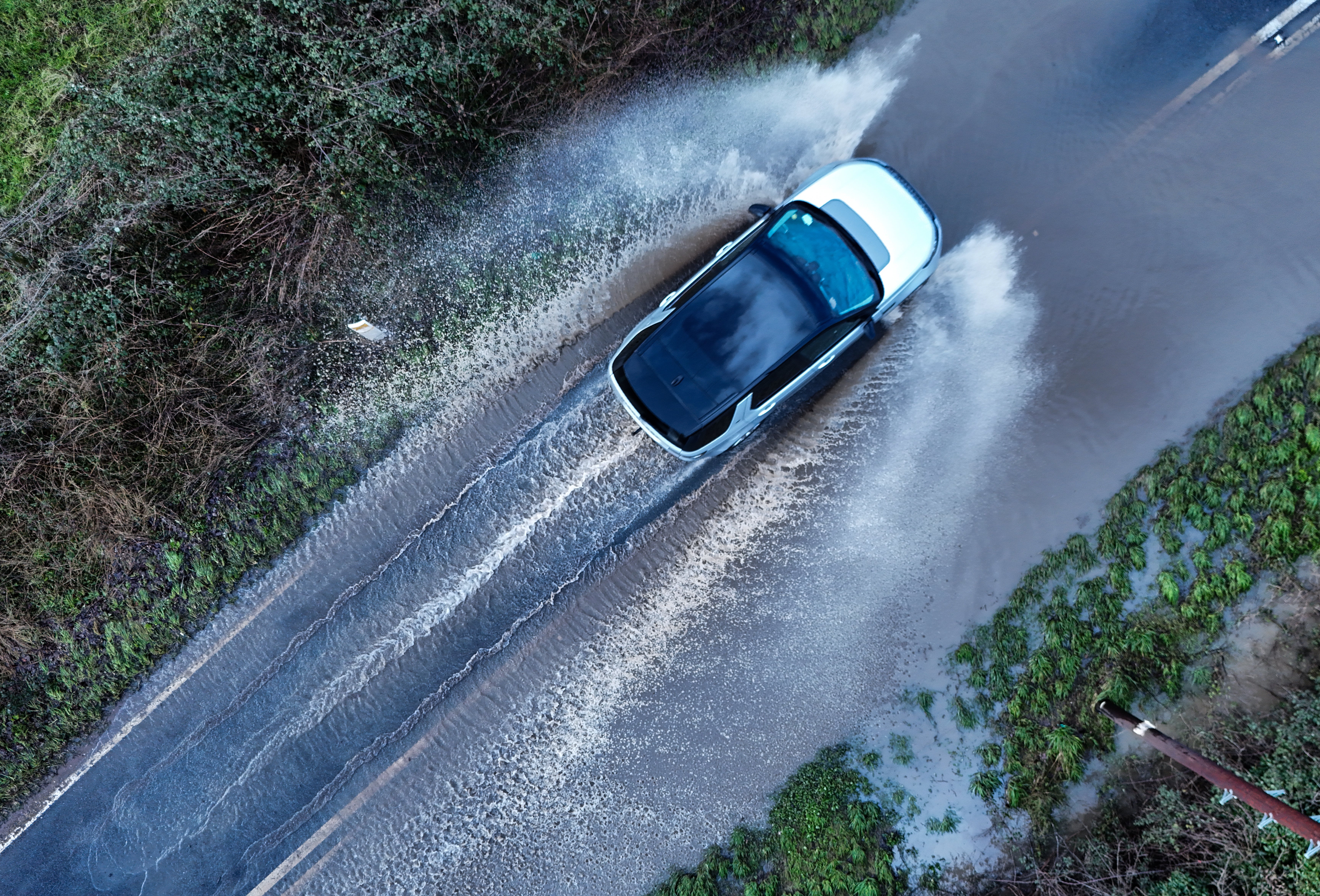 A vehicles drives through standing flood water near Eckington in Worcestershire