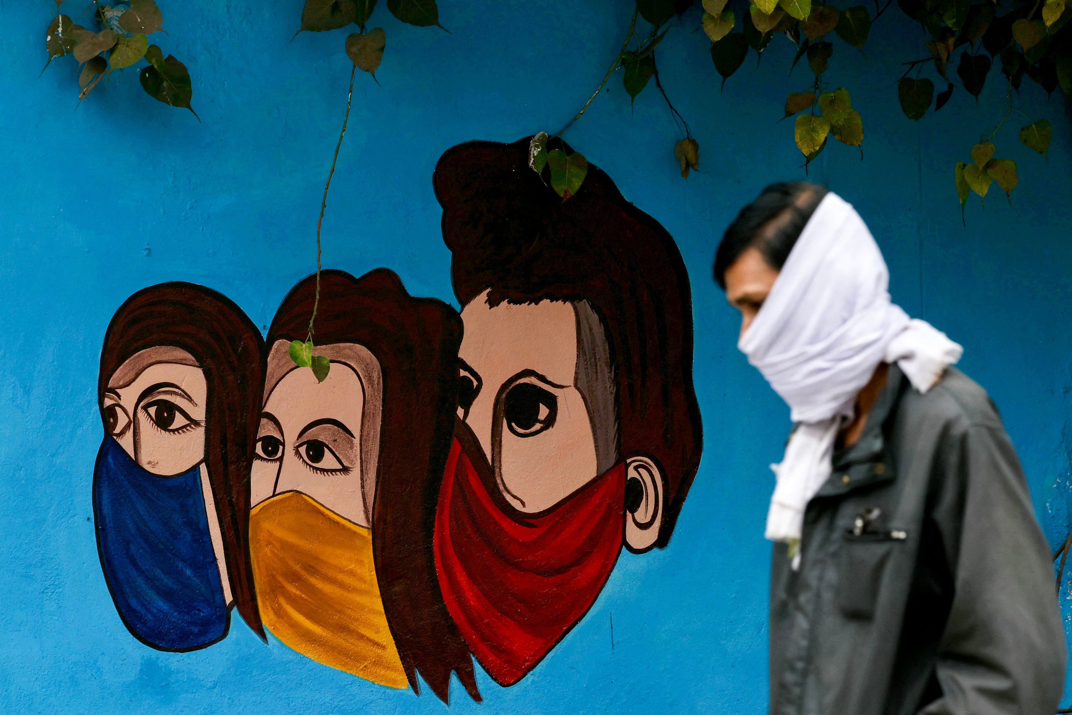 A person walks past a public health mural amid an outbreak of Human Metapneumovirus (HMPV) in India