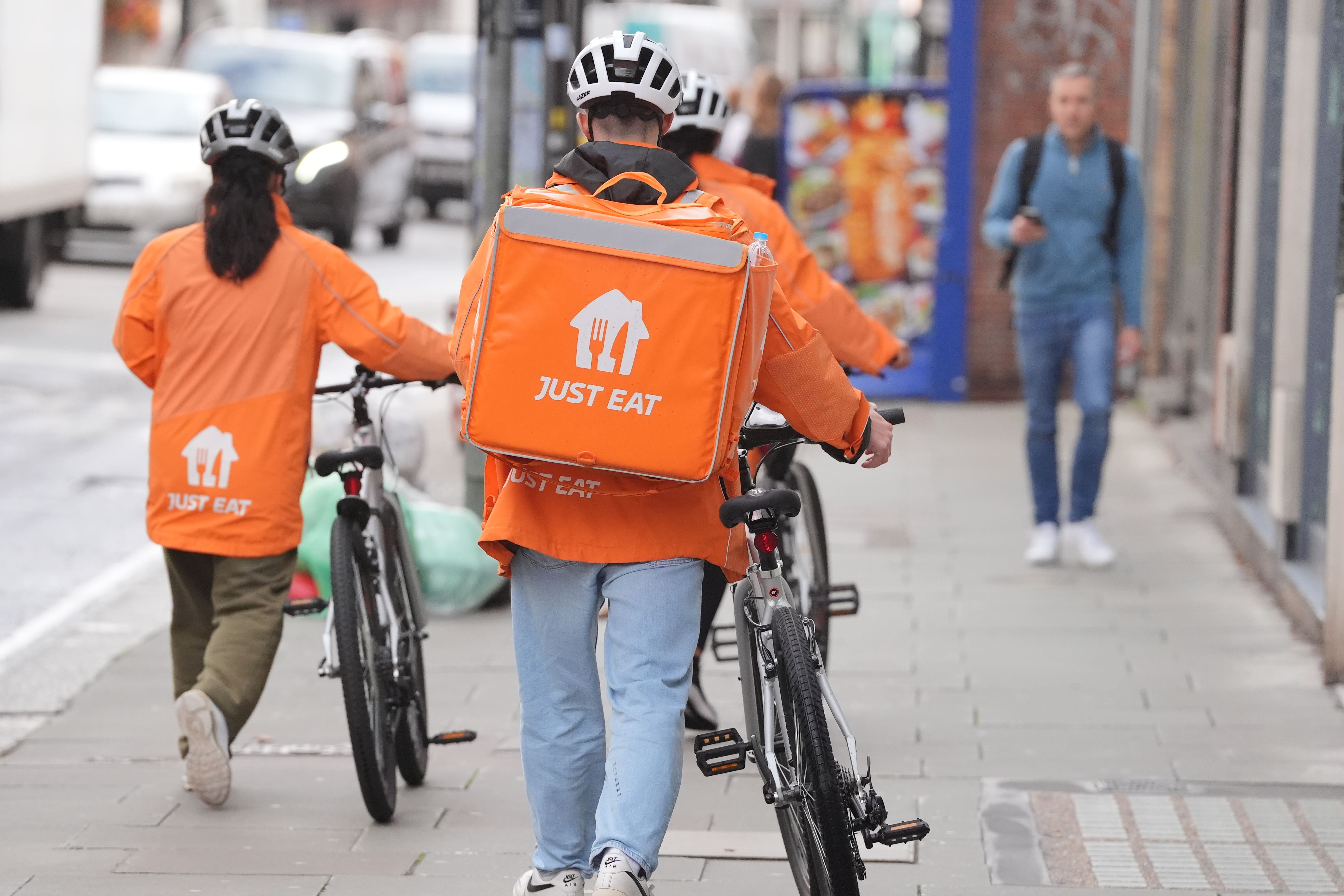 Just Eat delivery riders in London. The group completed the sale of its GrubHub arm (Jonathan Brady/PA)