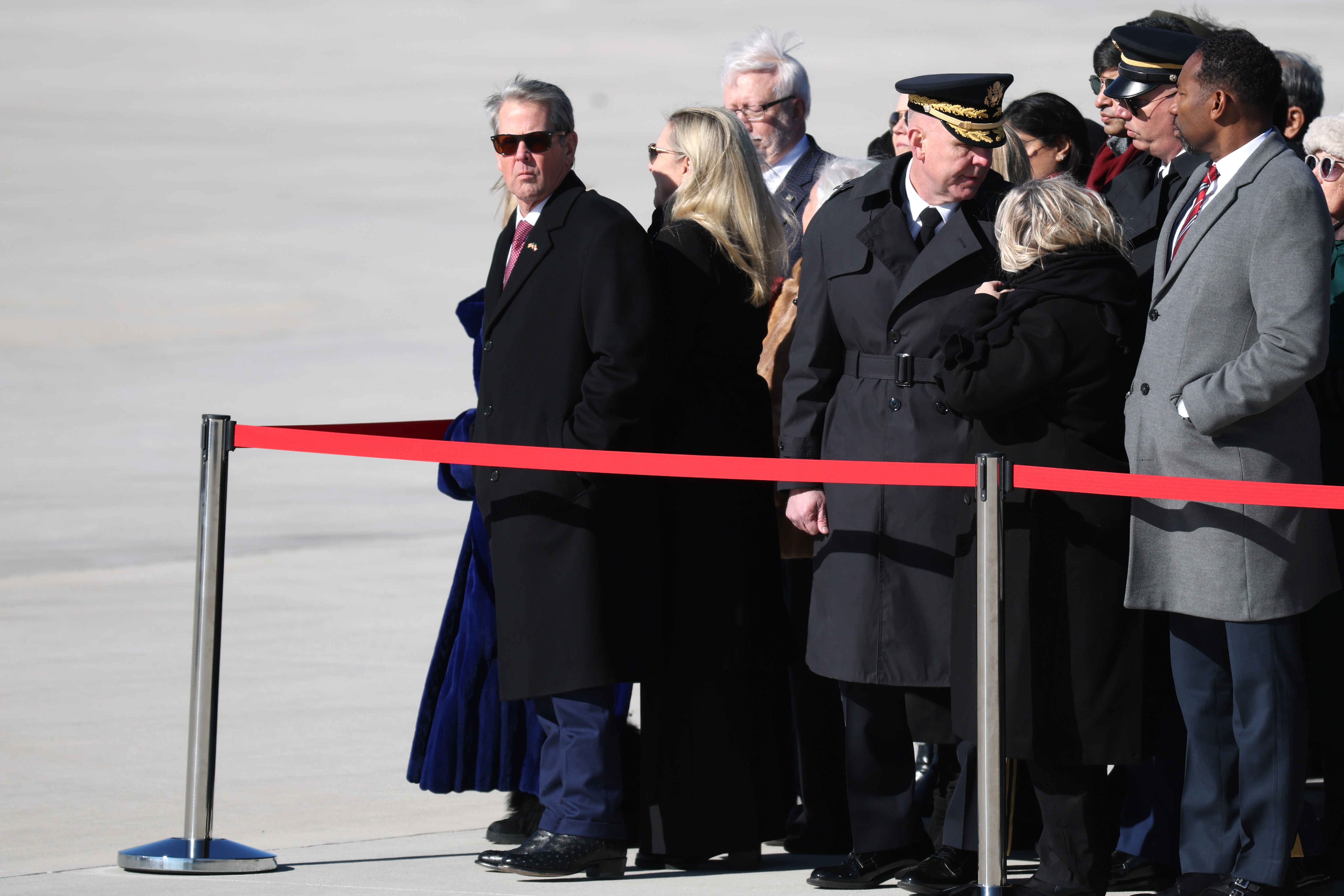 Georgia Gov. Brian Kemp (L) and others await the arrival of former U.S. President Jimmy Carter's casket as it is transported to Washington, DC at Dobbins Air Reserve Base on January 7, 2025 in Marietta, Georgia