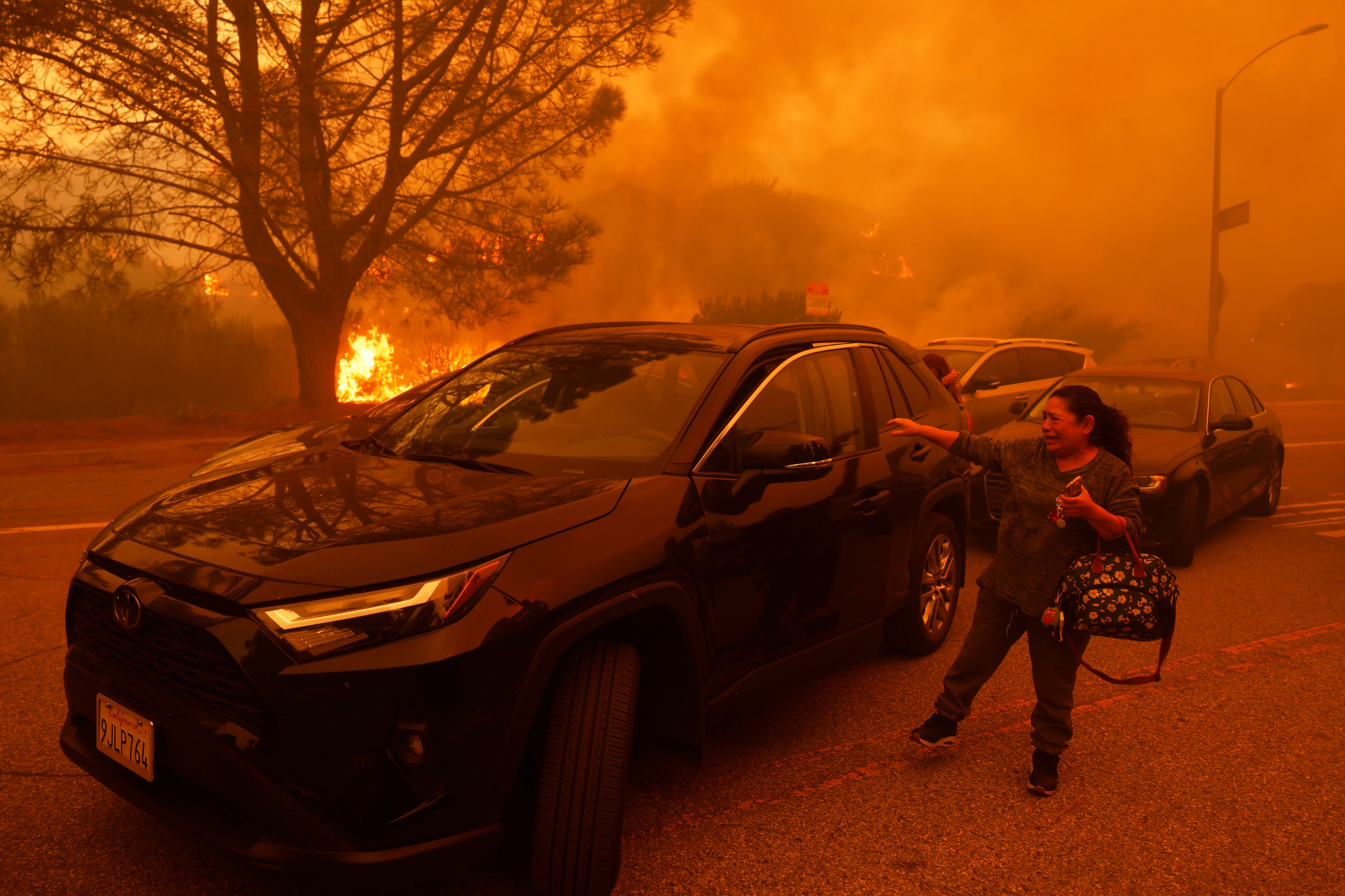 A woman cries as the Palisades Fire rages in Pacific Palisades, California, on Tuesday. The fire continued to spread quickly amid strong winds