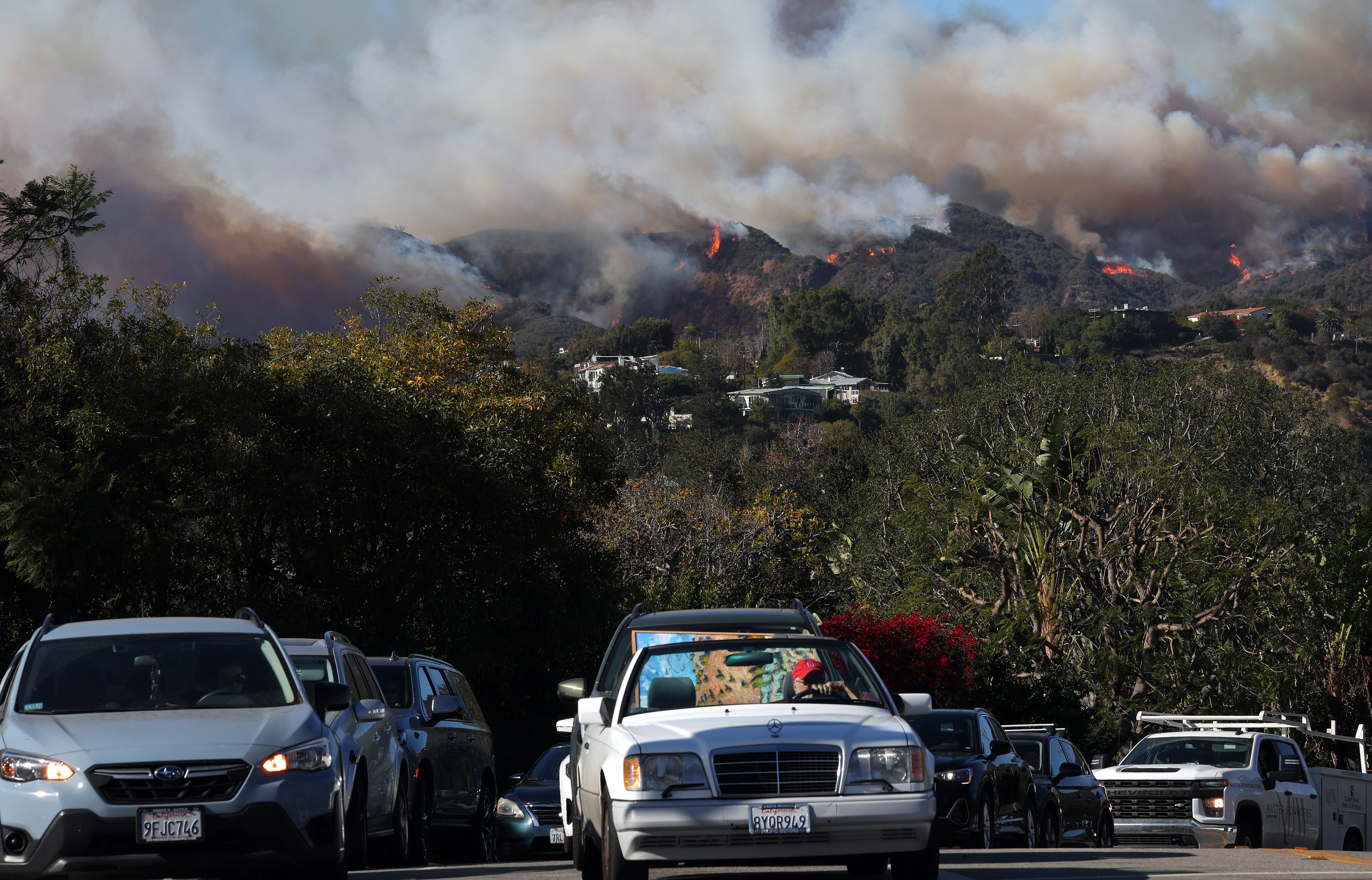 People drive out of harm’s way as the Palisades Fire burns in Pacific Palisades, California, on Monday. The fire had torn over 200 acres