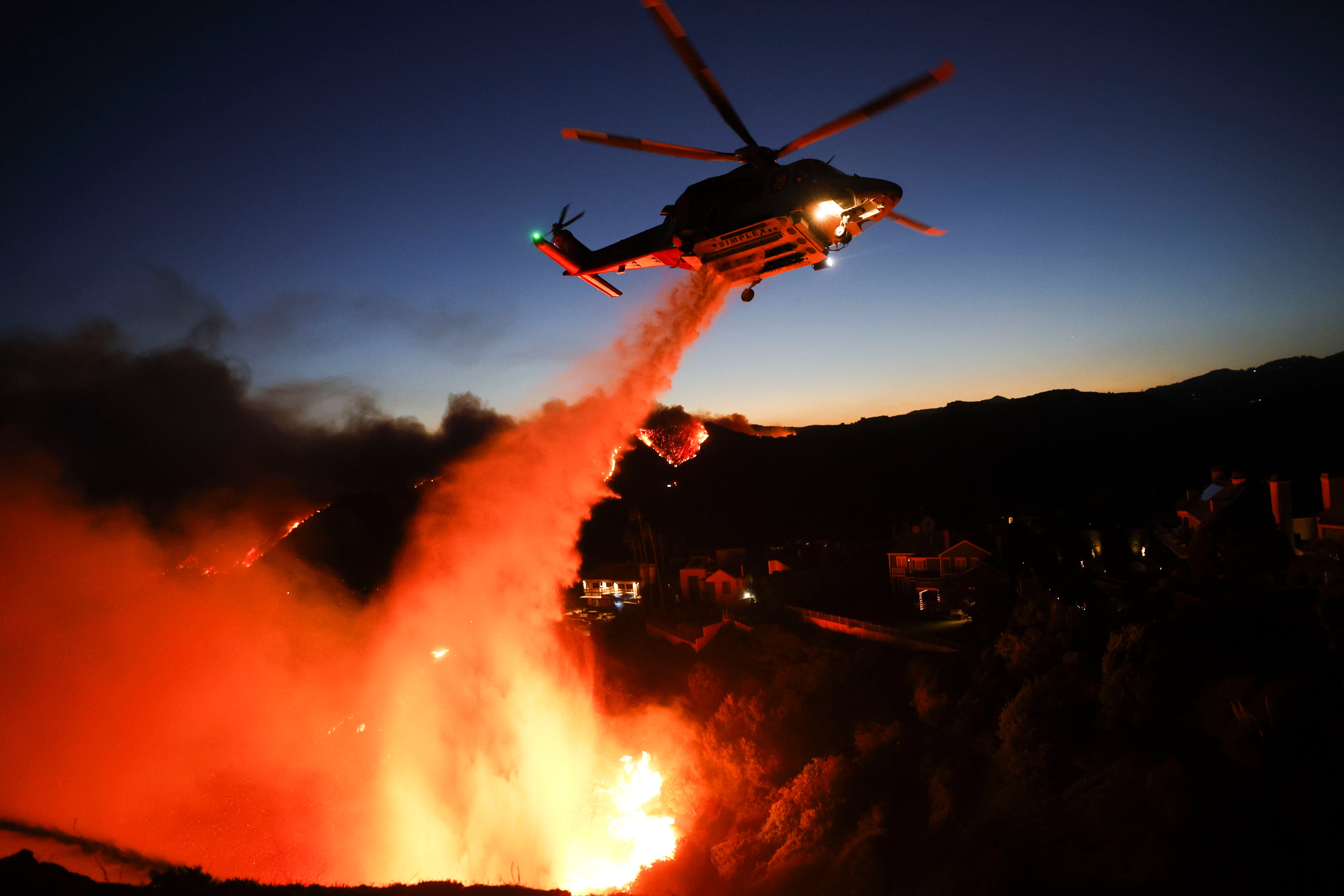 A Los Angeles County firefighting helicopter drops water to battle the Palisades wildfire