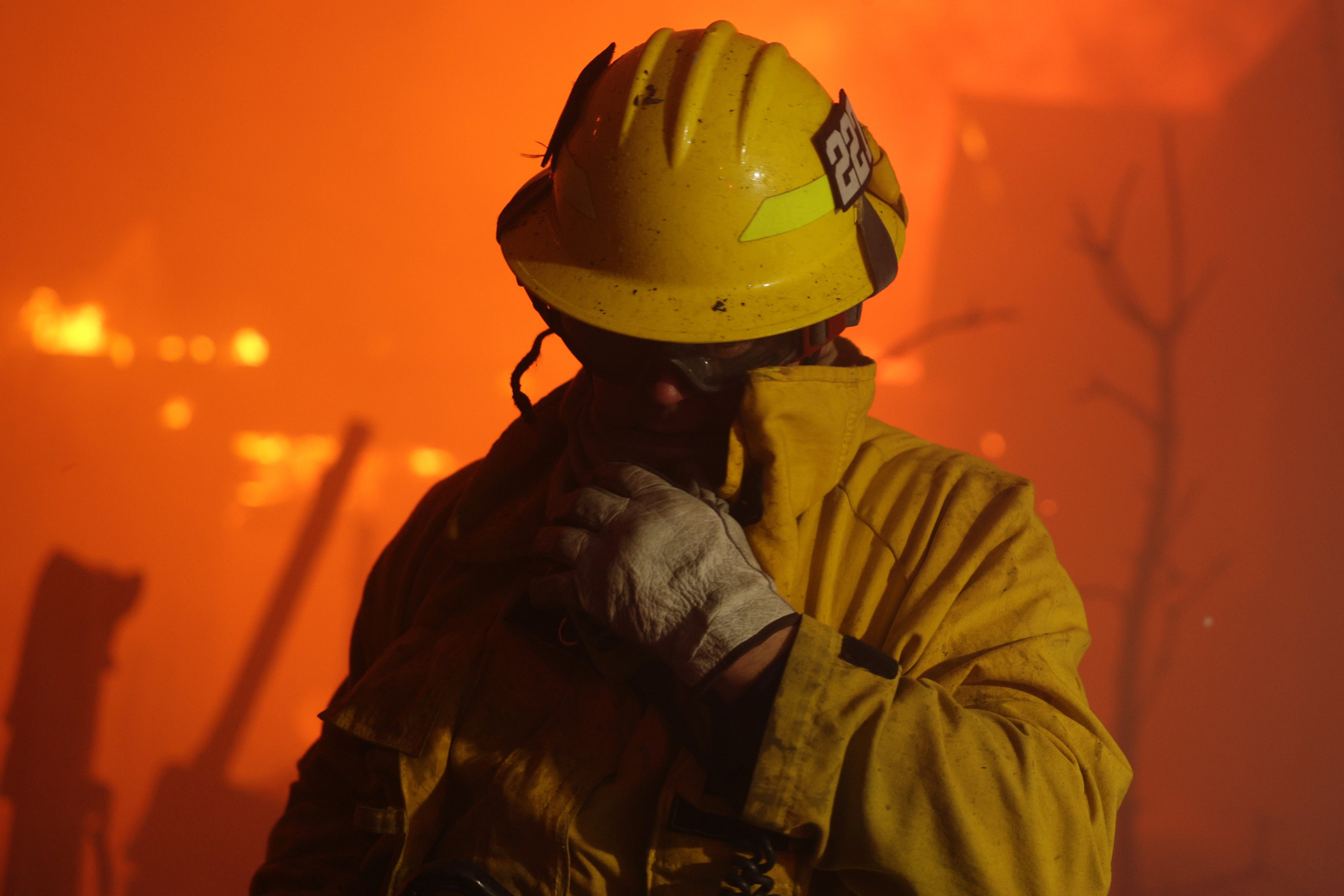 A firefighter reacts from smoke during the Palisades wildfire in Pacific Palisades