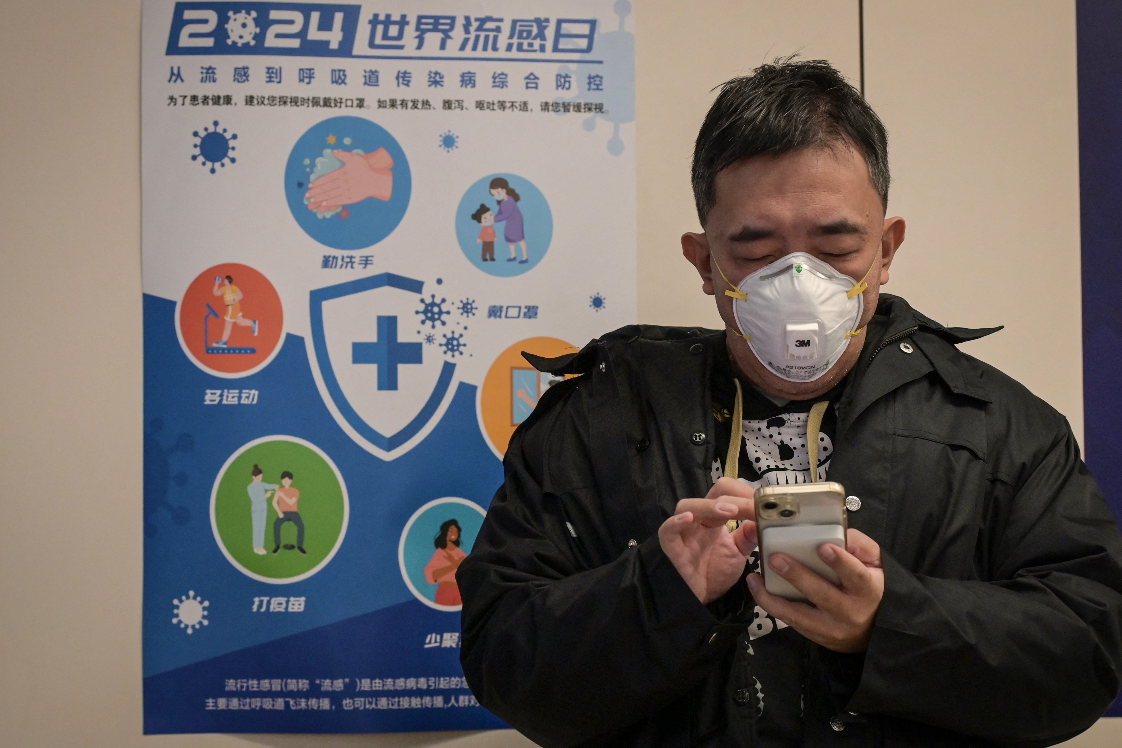 A man wearing a mask waits at an outpatient area of the respiratory department of a hospital in Beijing on January 8, 2025