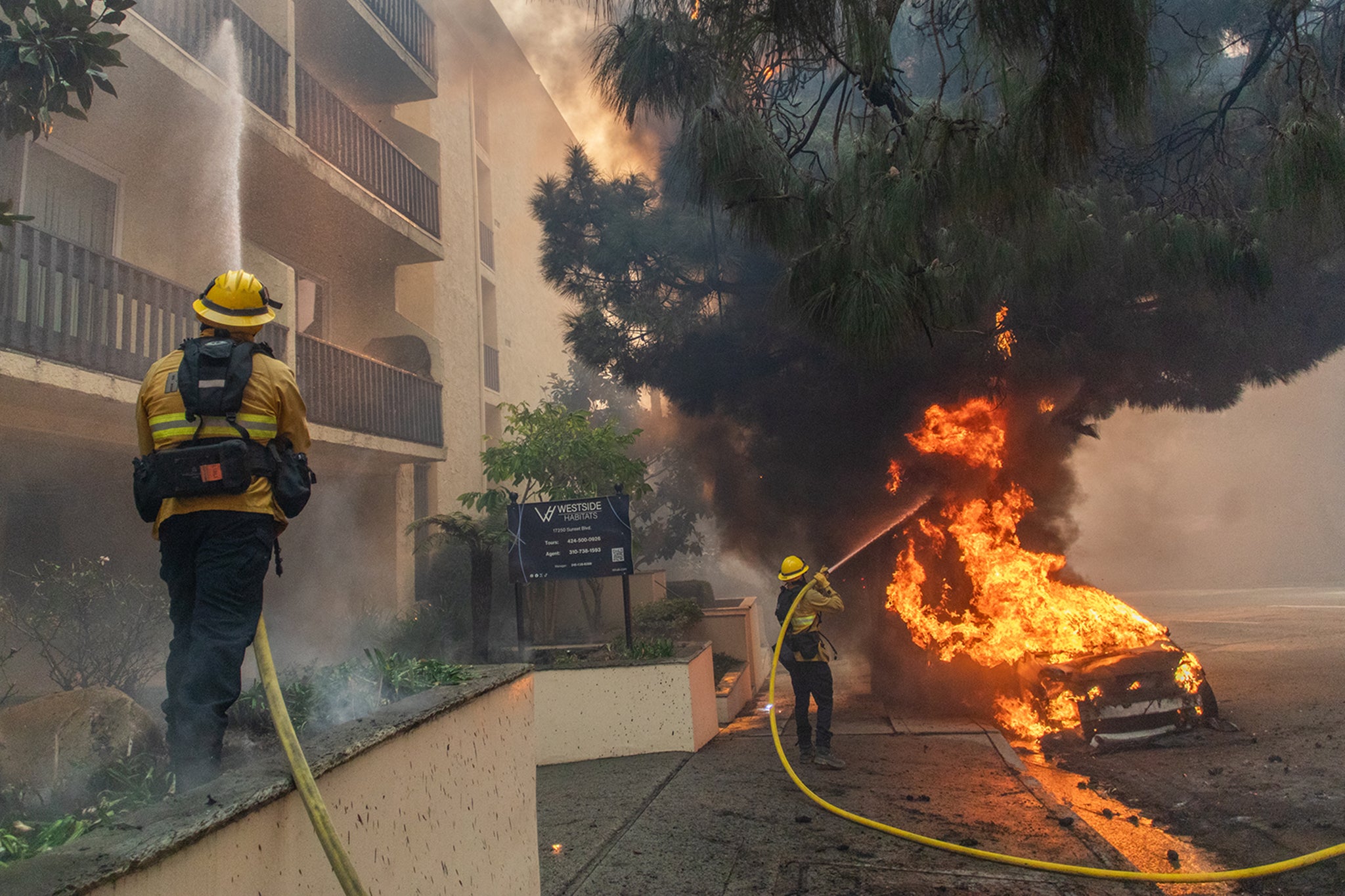 Firefighters spray water on a burning car on Sunset Boulevard. Los Angeles Mayor Karen Bass warned that the windstorm “is expected to worsen through the morning.” She said emergency shelters are available for those who have been evacuated due to the fires. As the largest three fires terrorize the region, the Woodley Fire also started burning in Los Angeles County just after 6 a.m. on Wednesday. It has already consumed 30 acres.