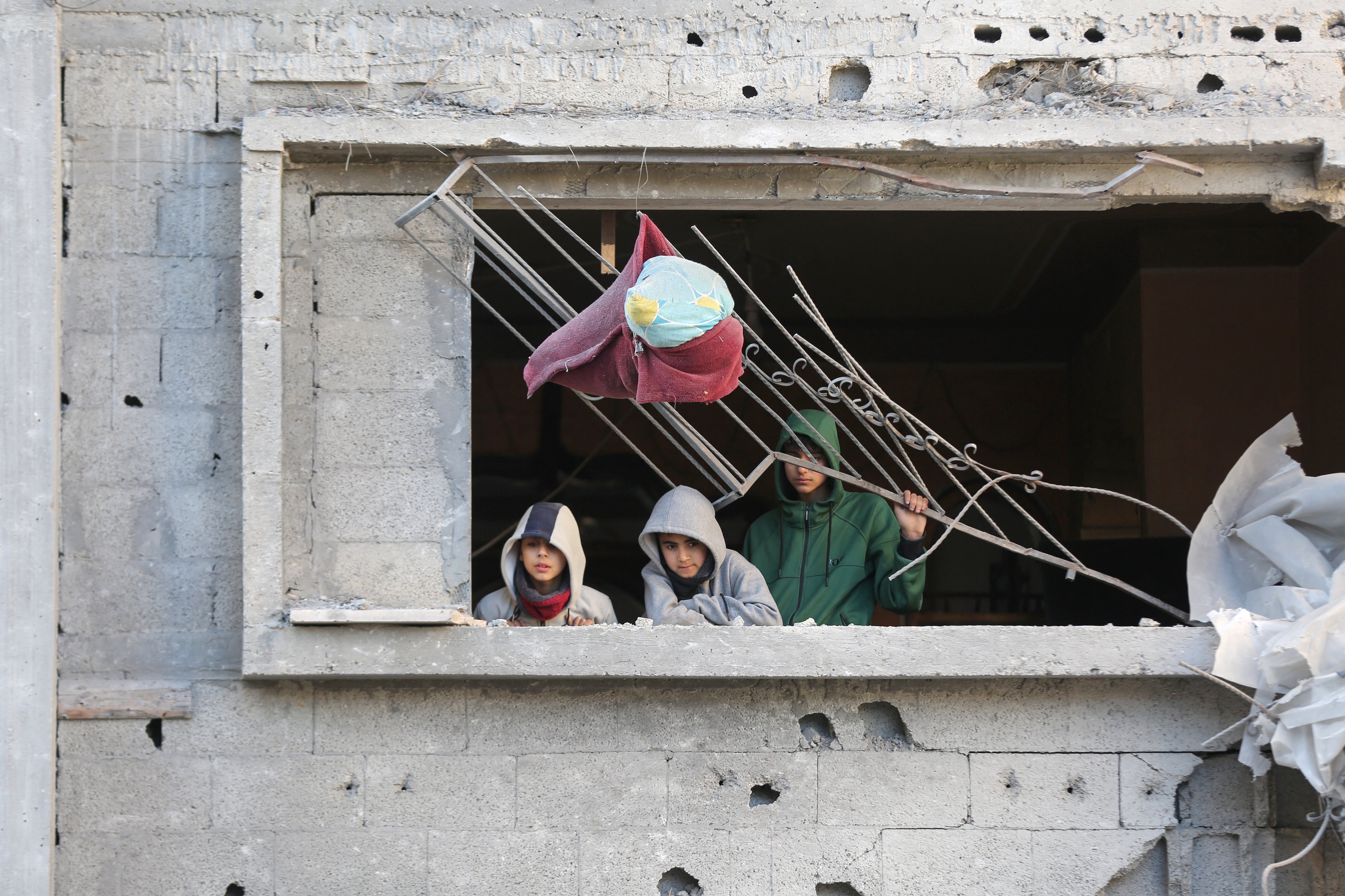 Three children look on from a damaged building after an Israeli airstrike on the Bureij camp for Palestinian refugees in the central Gaza Strip