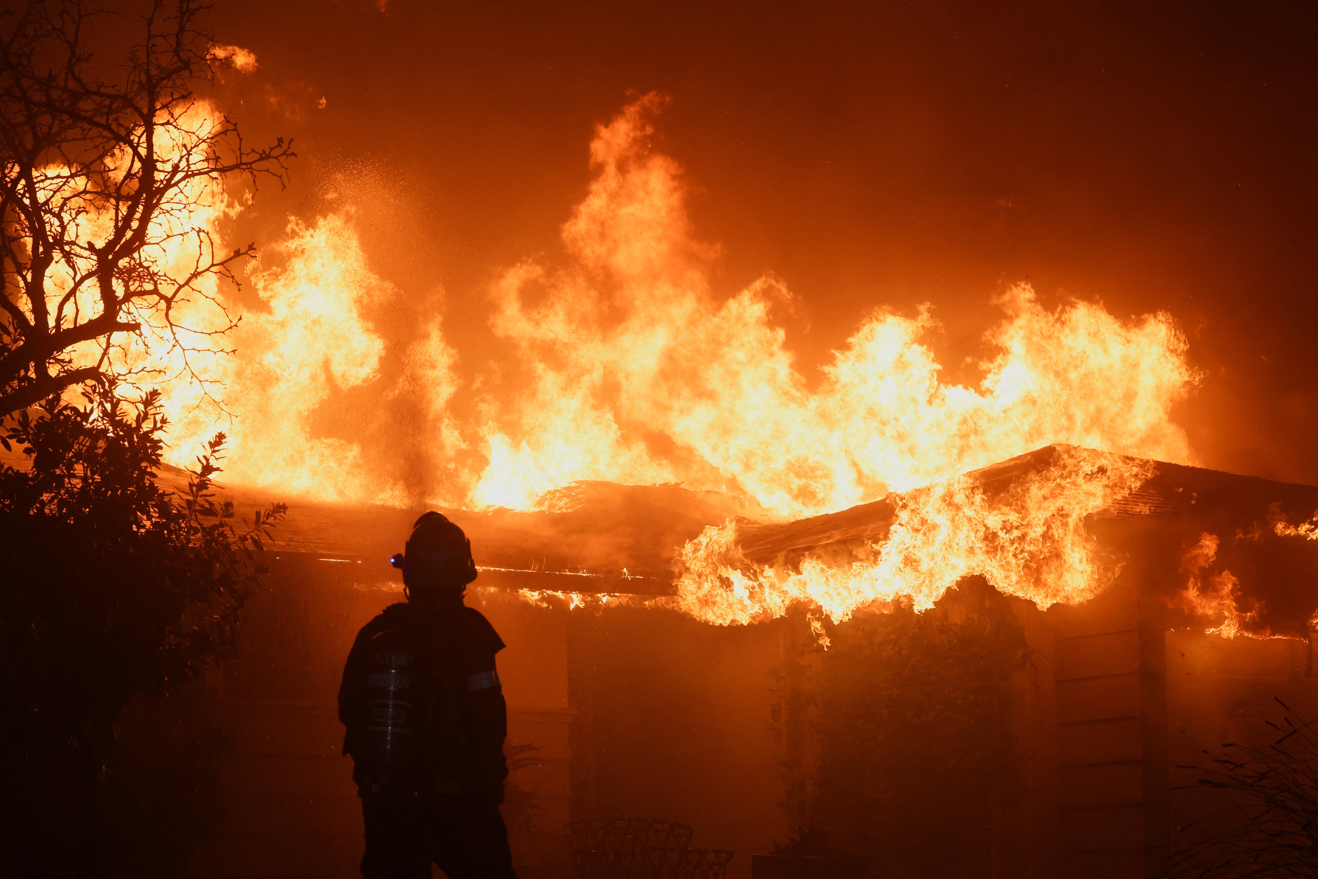 A firefighter works to extinguish flames as the Eaton Fire burns in Pasadena, California, on Wednesday. Evacuation orders around the blaze are expanding