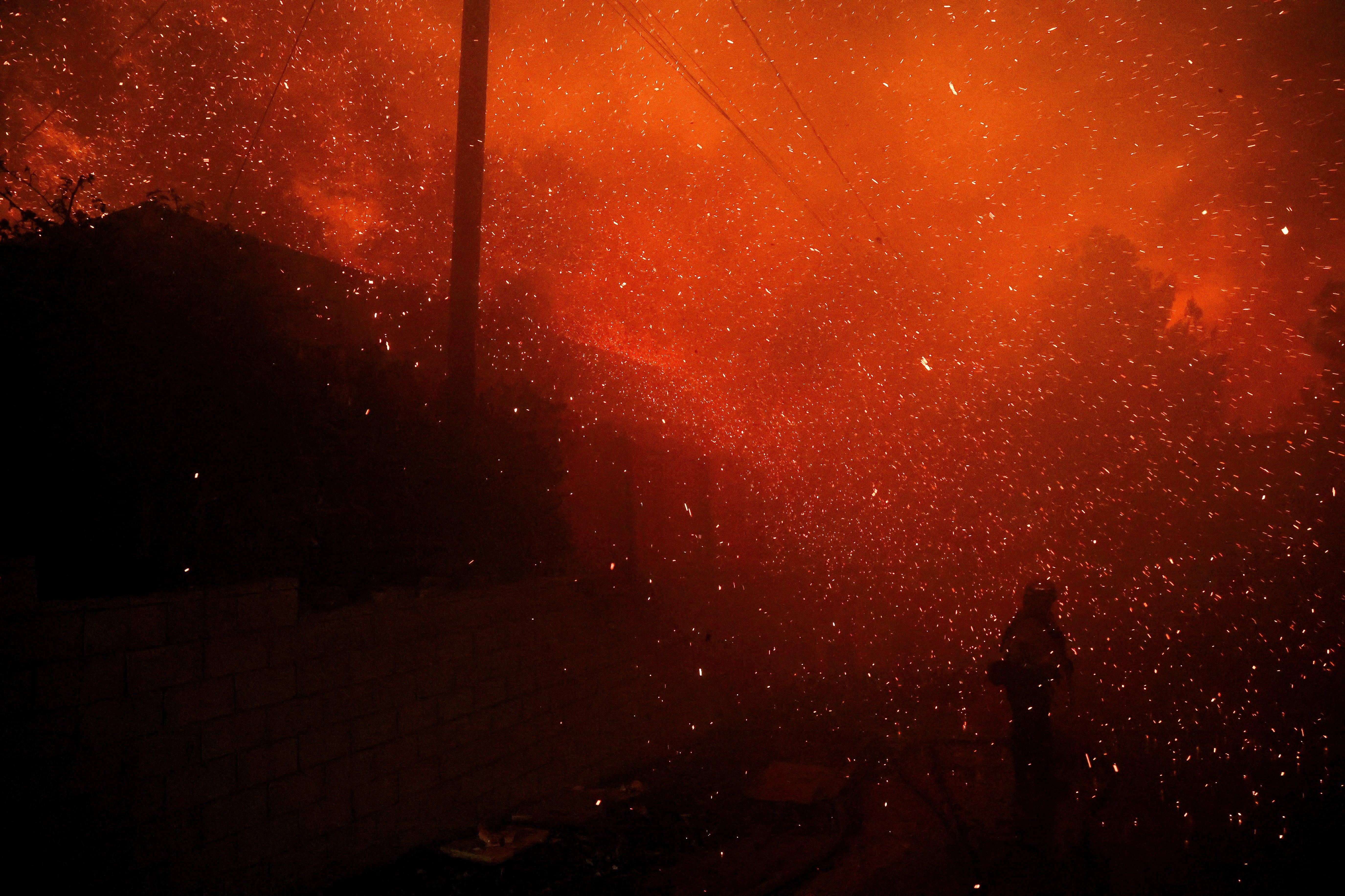 A firefighter stands among flying sparks as the Eaton Fire burns in Pasadena, California, on Tuesday. The fire has more than doubled since it started