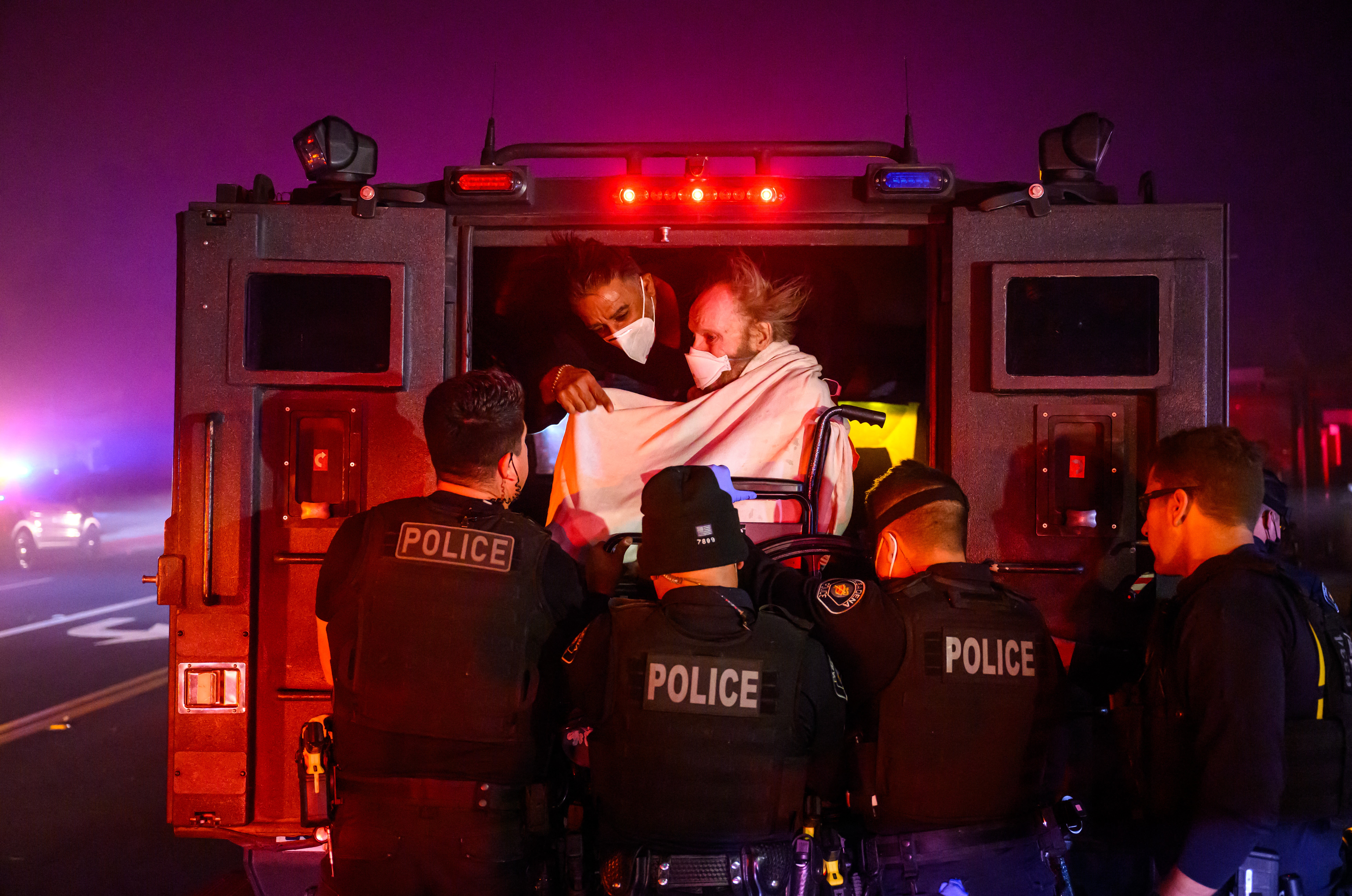 Elderly patients are quickly evacuated into an armored vehicle as embers and flames approach during the Eaton fire in Pasadena