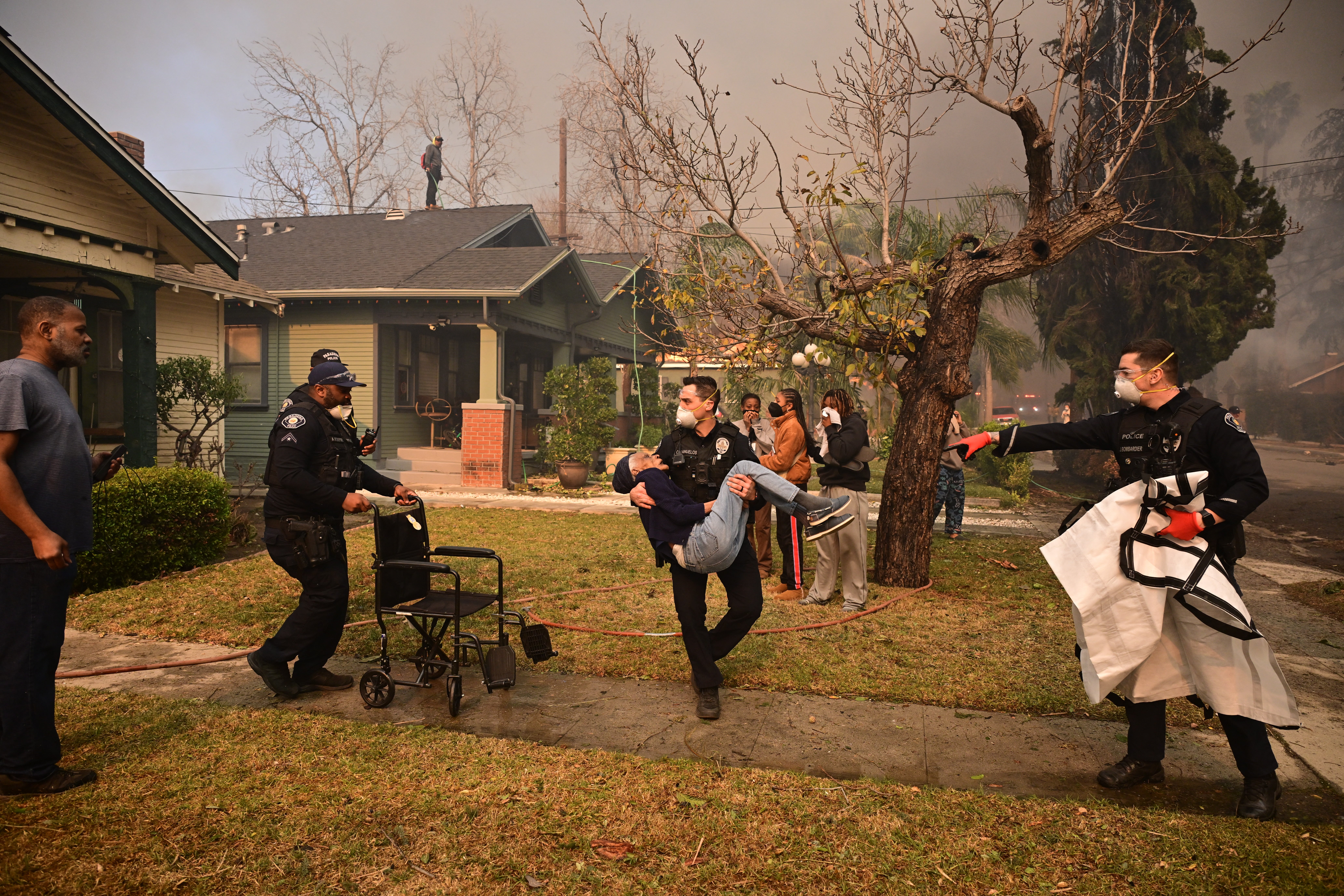 Police officers remove an eldery resident from her home during the Eaton Fire in Altadena, California, on January 8. “We were having dinner with the family and we just had to leave because the fire was coming so fast,” Darinka Whitmore from Eaton Canyon in Altadena, who fled with her husband and their four children, told The New York Times . “We just grabbed our backpacks and our kids and our doggies.”