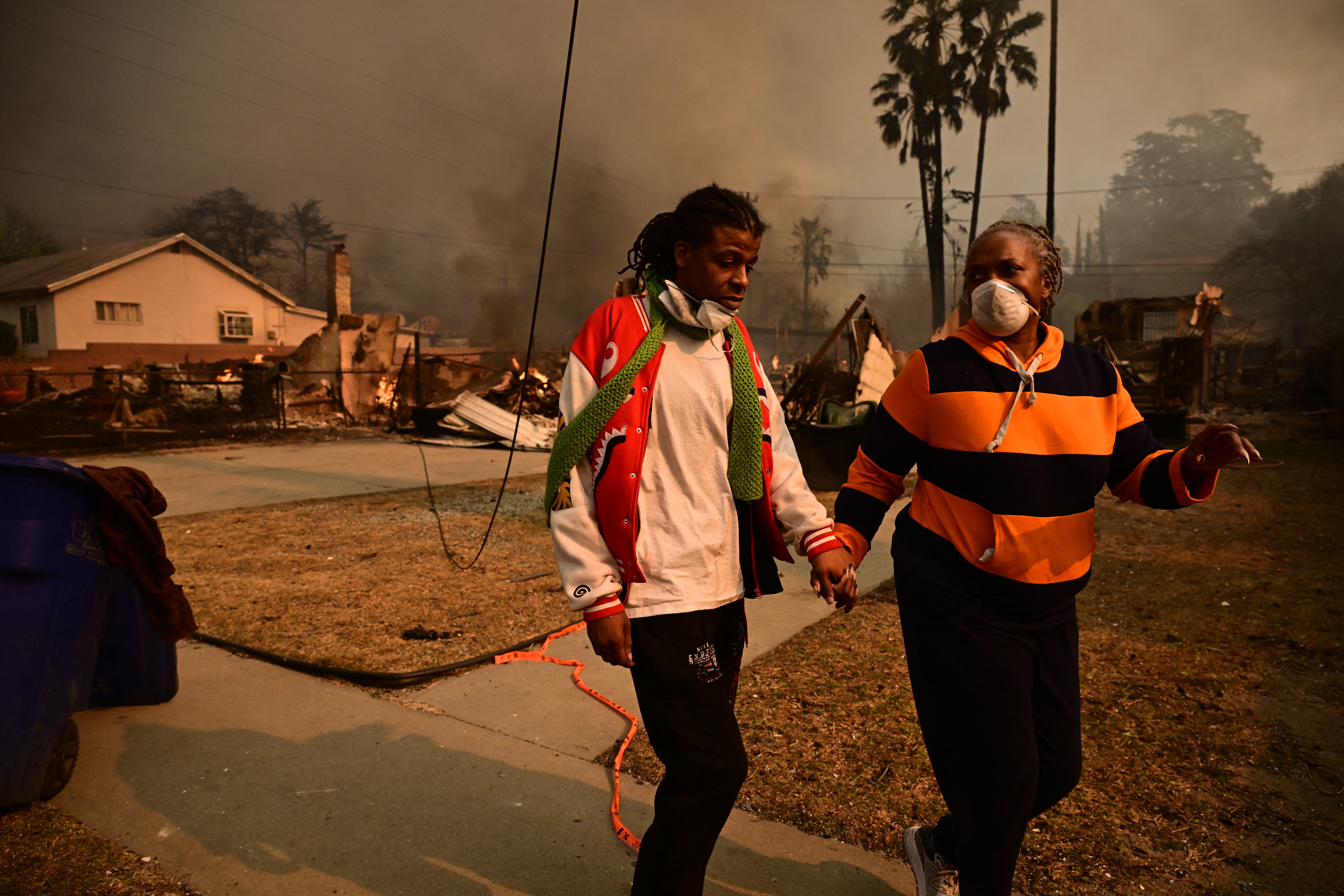 Residents walk past homes burnt by the Eaton Fire in Altadena, California, on Wednesday. The fire had spread over 10,600 acres