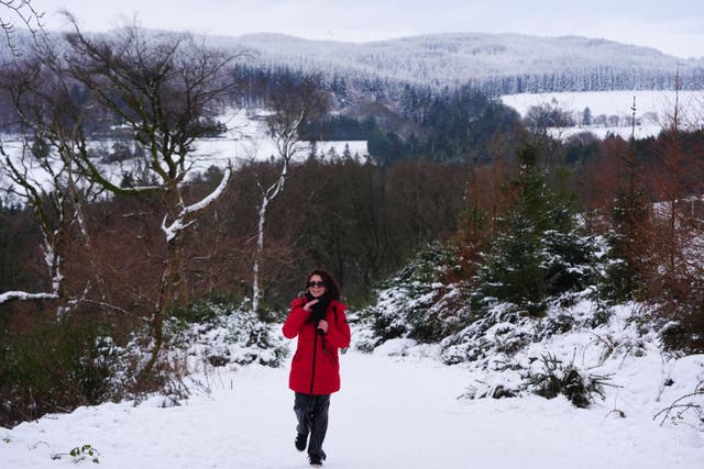 A person adjusts their scarf as they walk up towards the Hell Fire club in Dublin (Brian Lawless/PA)